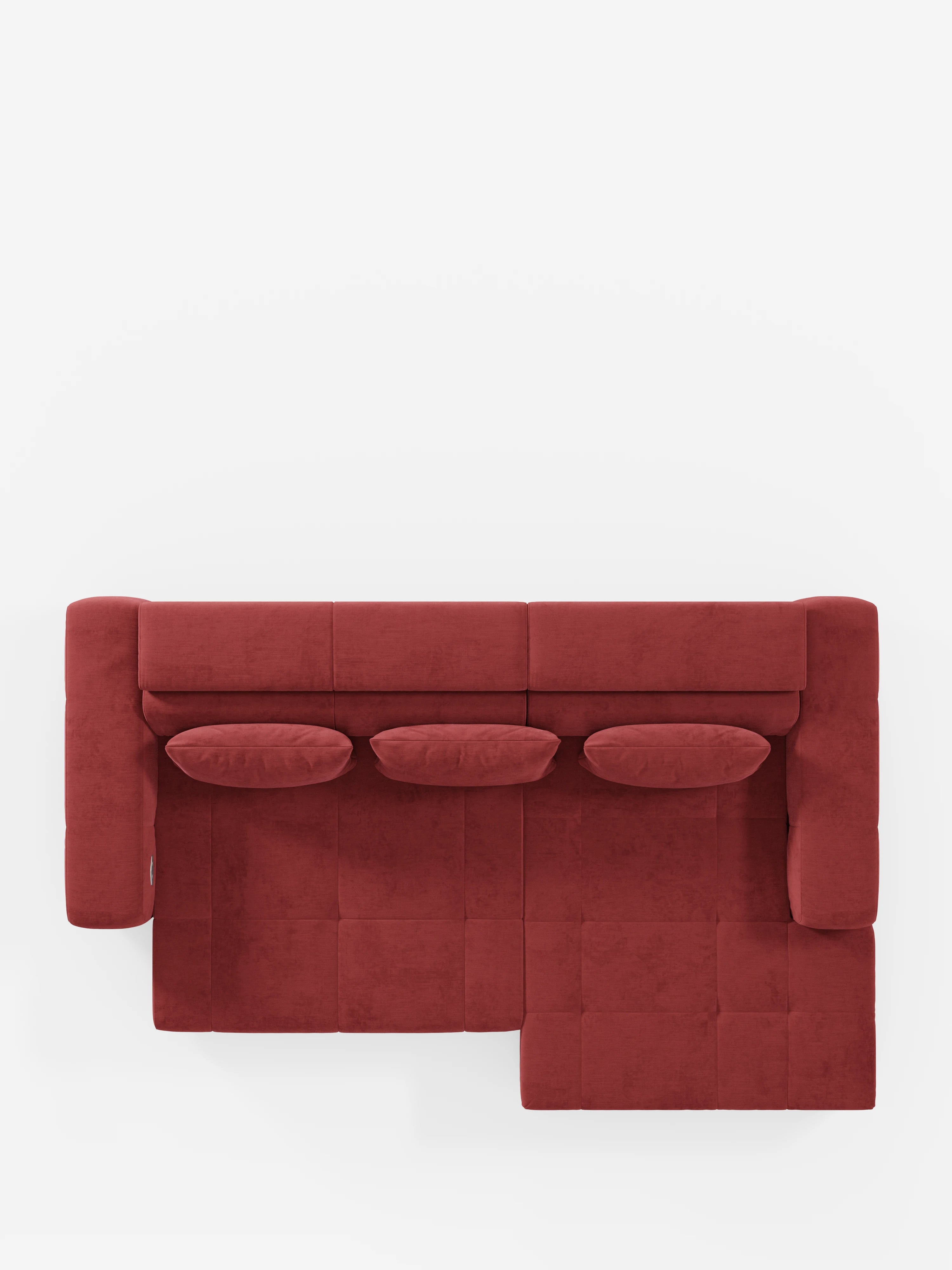 Vista dall'alto del divano angolare Monarch con penisola e funzione Relax elettrica per l'allungamento delle sedute di divitt.sbs, rivestito in morbido tessuto T31 resistente alle macchie. Questo divano componibile dal rosso vivace presenta una chaise longue sul lato destro, tre cuscini cilindrici abbinati, poggiatesta reclinabili e sedute allungabili elettricamente. Il suo design geometrico moderno risalta sullo sfondo bianco a tinta unita, conferendogli un aspetto lussuoso e spazioso.