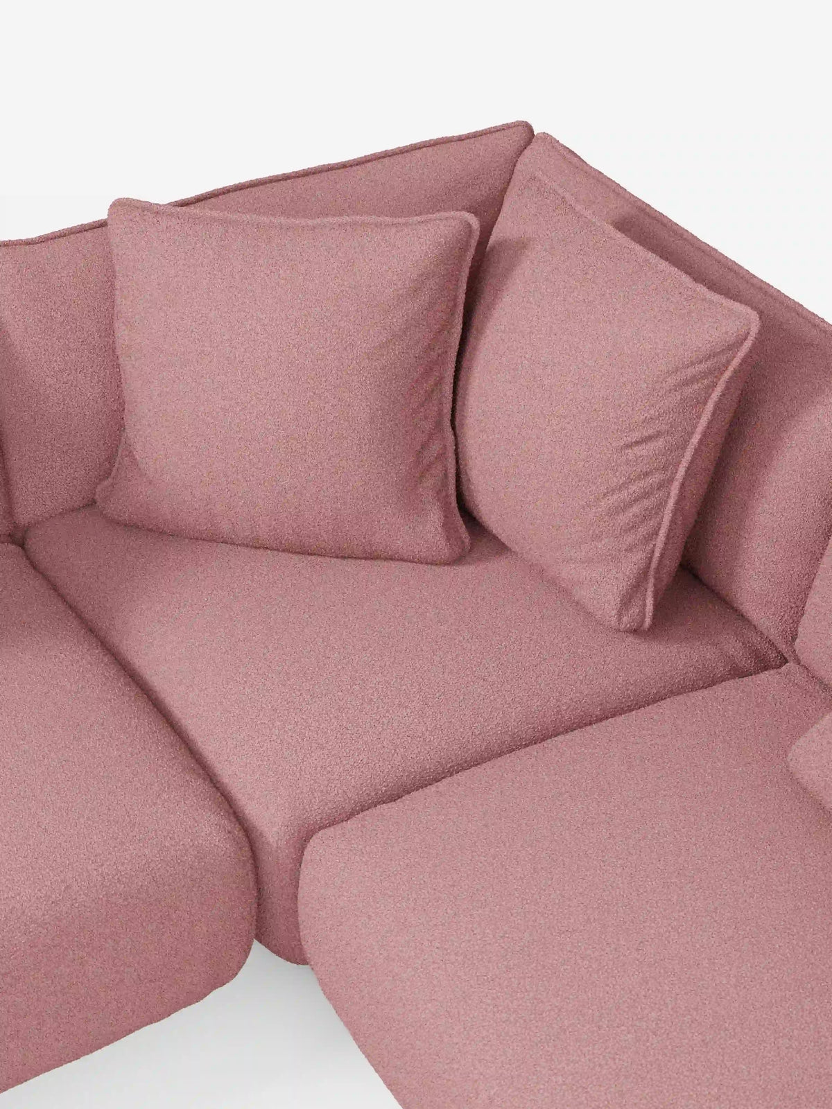 Un primo piano del divano angolare panoramico componibile Nimbus con penisola e angolo in tessuto smacchiabile T33 di divitt.sbs mette in risalto il suo tessuto morbido, strutturato e resistente alle macchie, in colore rosa. Il divano componibile presenta due grandi cuscini coordinati, disposti ordinatamente nell’angolo contro lo schienale. Le linee pulite e il design moderno sottolineano l’eccezionale qualità e l’artigianalità italiana che contraddistinguono i mobili divitt.sbs.