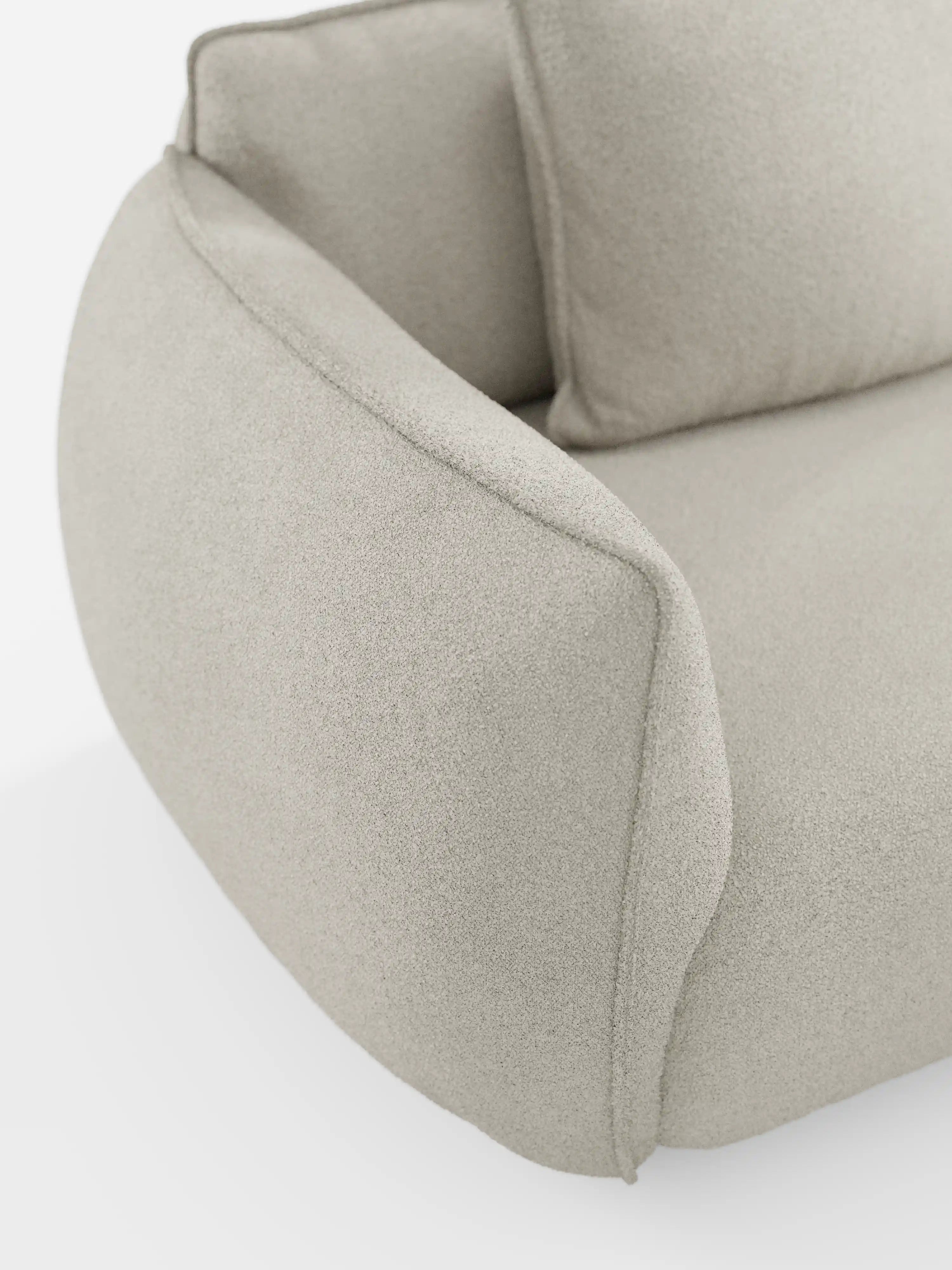 Primo piano del divano modulare e componibile a 3 posti Nimbus da 250 cm di divitt.sbs, rivestito in tessuto beige chiaro, sfoderabile, con finitura antimacchia effetto cotone (tessuto smacchiabile effetto cotone t33). Caratterizzato da una silhouette moderna e sinuosa con braccioli e cuscini arrotondati e morbidi, la sua trama soffice e leggermente felpata risalta sullo sfondo bianco, mettendo in risalto il design liscio e contemporaneo.