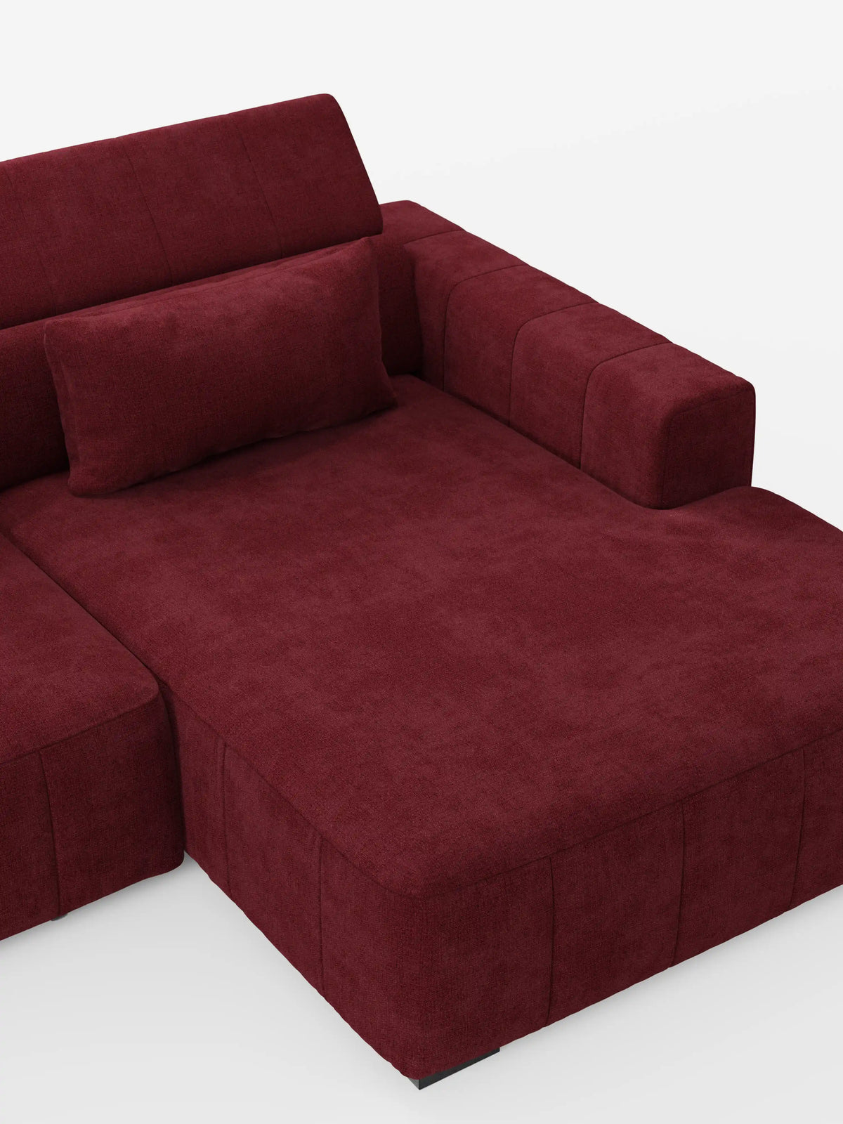 In questa immagine è raffigurato il divano angolare con penisola e sedute allungabili con relax elettrico “Doric” di divitt.sbs. Rivestito in tessuto T23 rosso intenso e resistente alle macchie, il divano presenta un'ampia zona relax tipica di un «divano con penisola», con sedute allungabili elettricamente e poggiatesta regolabili. Un cuscino rettangolare abbinato poggia contro lo schienale, su uno sfondo bianco a tinta unita.