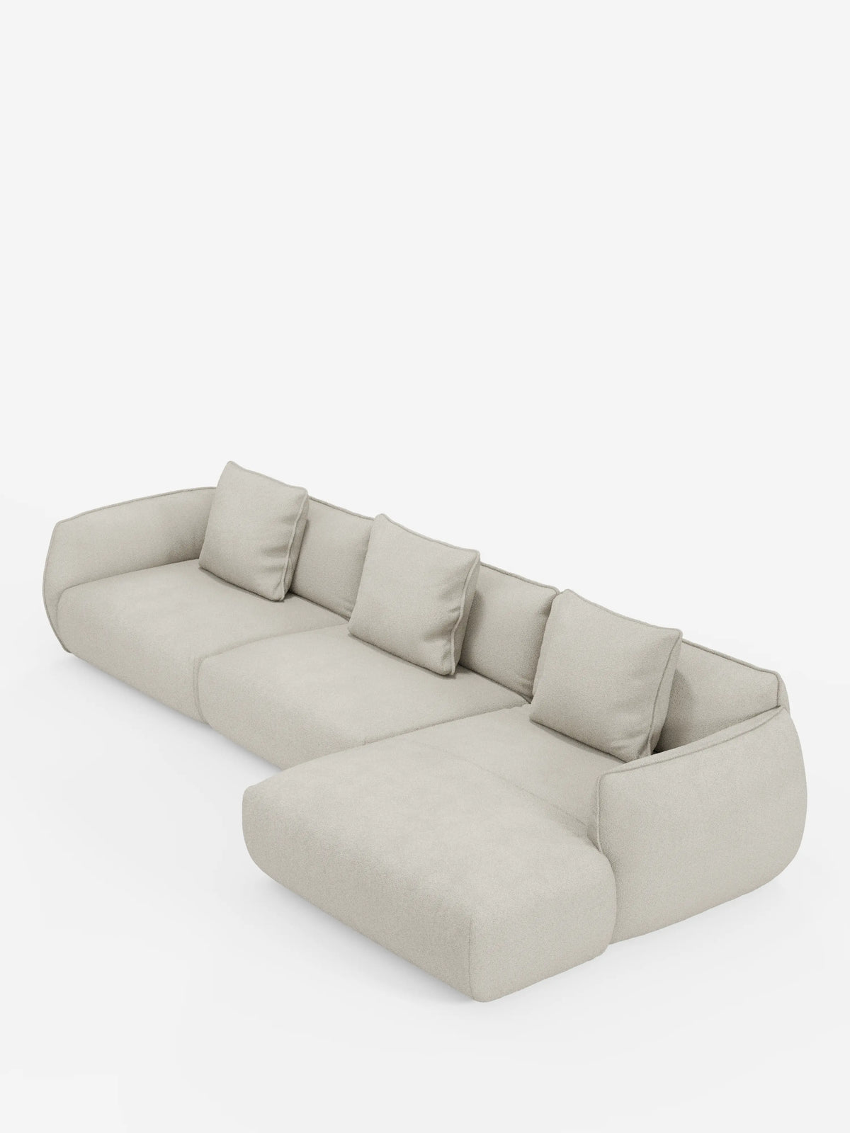 Un moderno divano angolare Nimbus con penisola componibile, rivestito in morbido tessuto effetto cotone smacchiabile T33 di divitt.sbs, presentato in una tonalità beige chiaro con quattro cuscini dello schienale e una chaise longue allungata sul lato destro, su uno sfondo bianco a tinta unita.