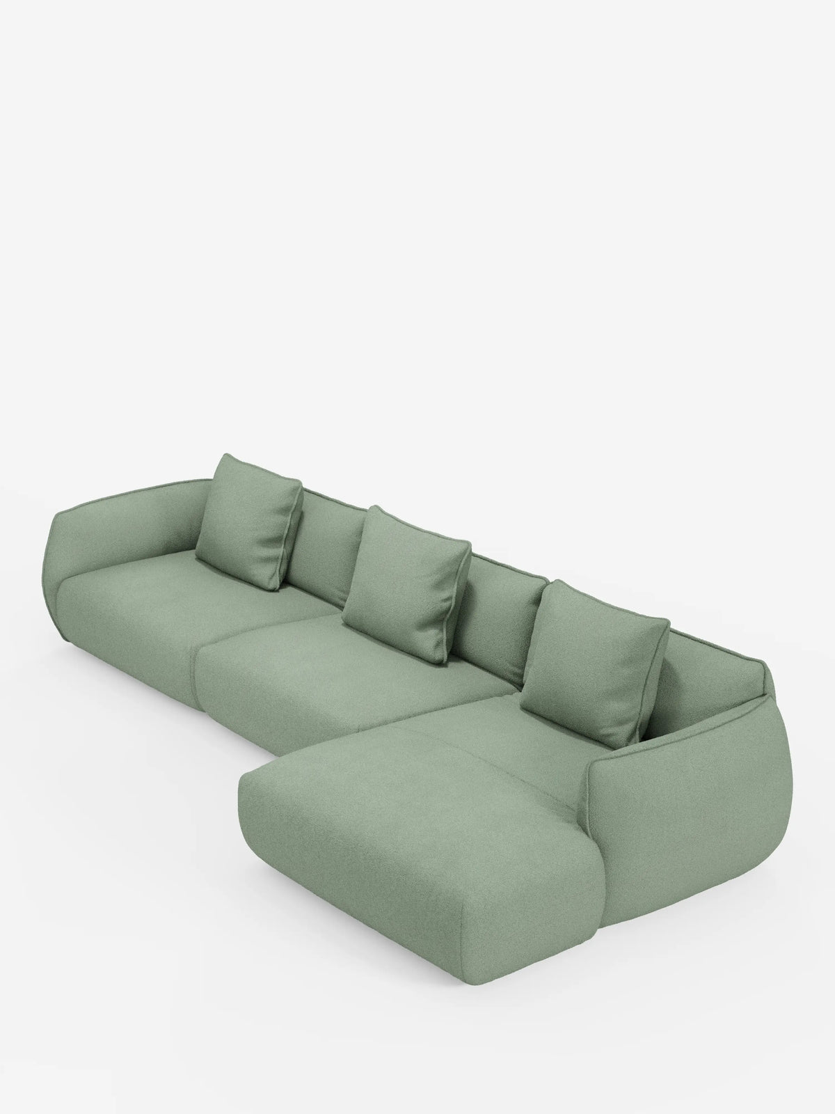 Un divano angolare Nimbus moderno, di colore verde chiaro, con penisola componibile, realizzato in morbido tessuto effetto cotone lavabile T33 di divitt.sbs, caratterizzato da quattro cuscini quadrati per lo schienale e da una chaise longue allungata sulla destra, su uno sfondo bianco a tinta unita. Questo divano contemporaneo presenta bordi arrotondati e linee pulite e dal profilo basso.