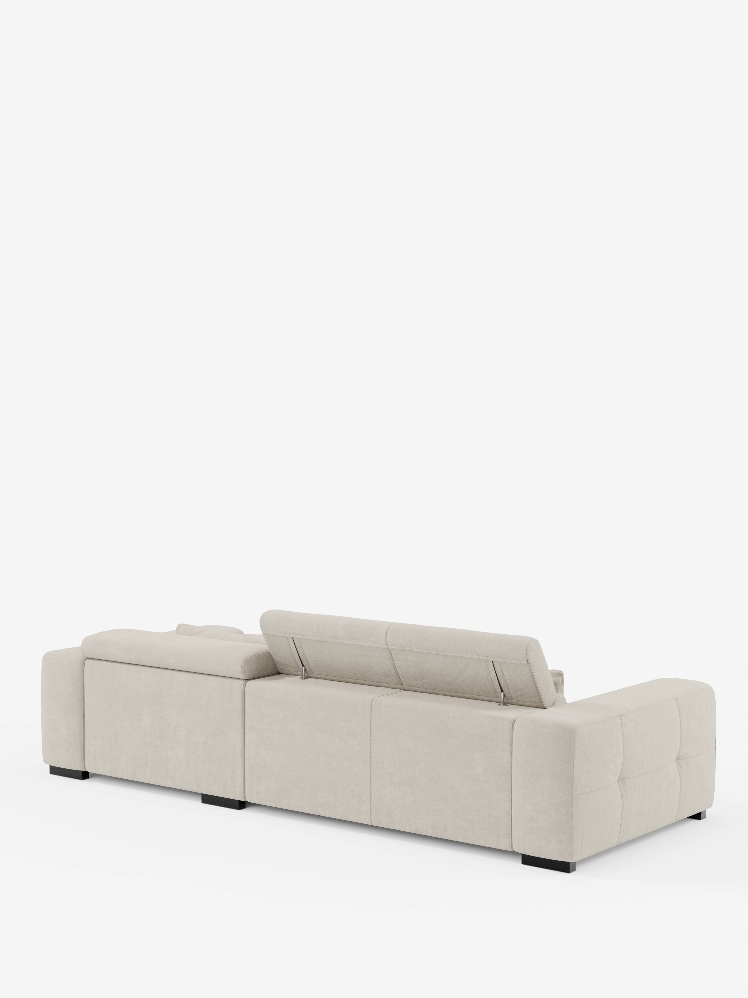 Il moderno divano angolare Monarch in beige chiaro con penisola e sistema Relax Elettrico per l’allungamento delle sedute, firmato divitt.sbs, si caratterizza per un profilo basso, ampi braccioli e un poggiatesta parzialmente rialzato e reclinabile. Il divano poggia su gambe corte nere e si stacca su uno sfondo bianco a tinta unita.