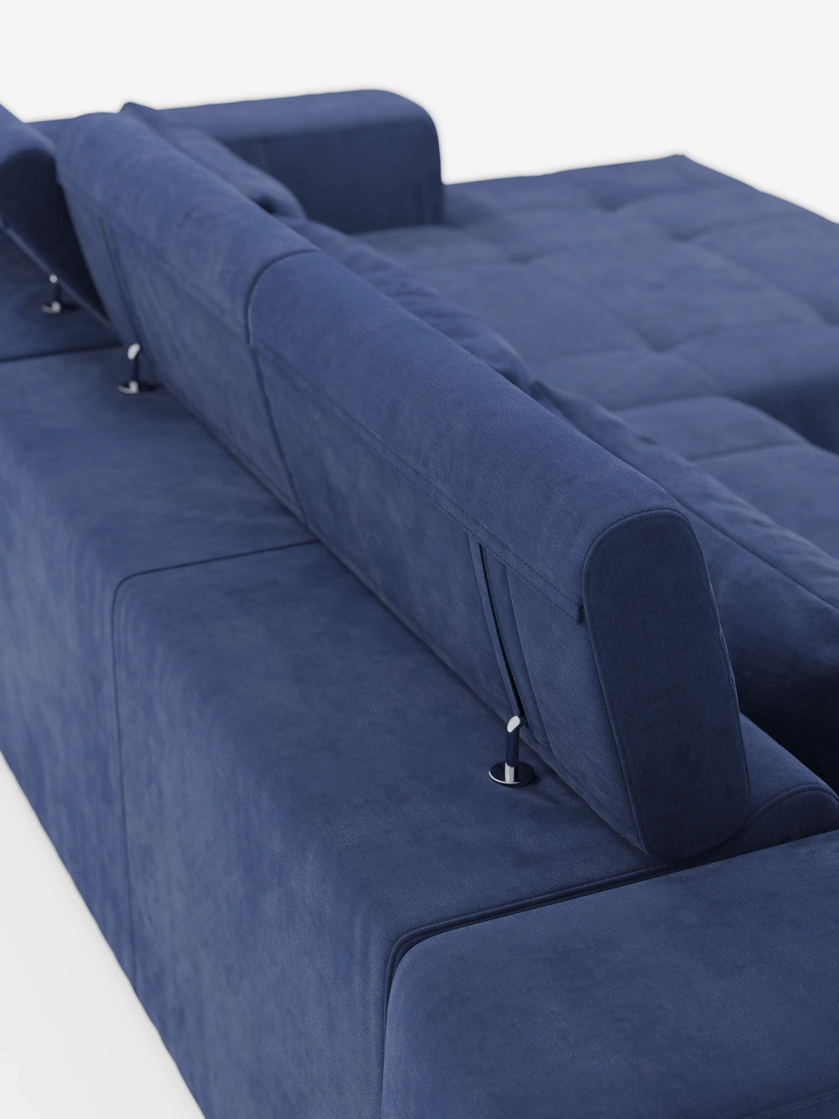 Un primo piano del divano angolare Monarch con penisola e sistema Relax Elettrico per l'allungamento delle sedute di divitt.sbs, rivestito in morbido tessuto T31 blu intenso e resistente alle macchie, è ripreso di profilo dalla parte posteriore. I poggiatesta reclinabili regolabili sono fissati con supporti metallici a vista, mentre la morbida superficie di seduta si estende fino a formare una chaise longue. Sfondo bianco.
