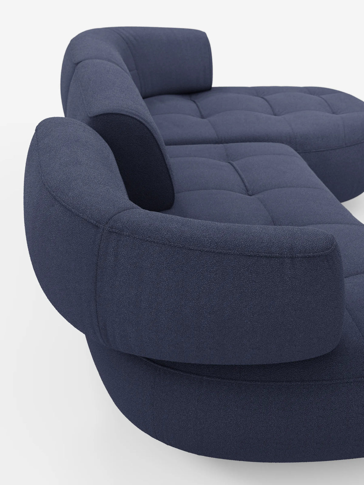 Un divano angolare Croissant blu scuro dal design a fagiolo e schienali traslanti in morbido tessuto effetto cotone smacchiabile T33, con un design curvo a forma di fagiolo, schienali modulari arrotondati e una seduta trapuntata con bottoni su sfondo bianco.