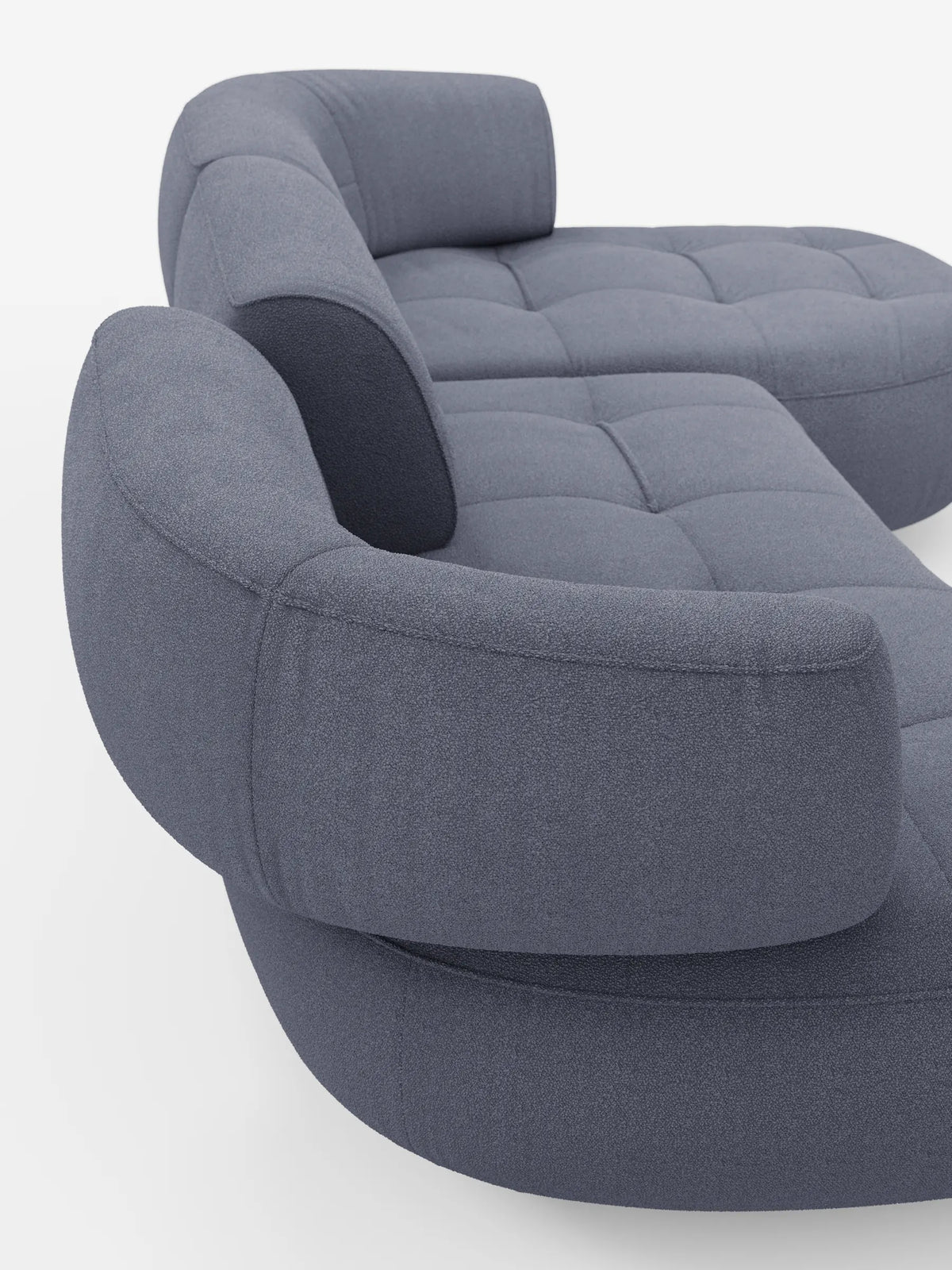 Un divano angolare Croissant di colore grigio-blu, dalla forma a fagiolo, con schienali scorrevoli in morbido tessuto effetto cotone lavabile, modello T33, caratterizzato da una finitura in tessuto testurizzato, schienali curvi e seduta trapuntata.