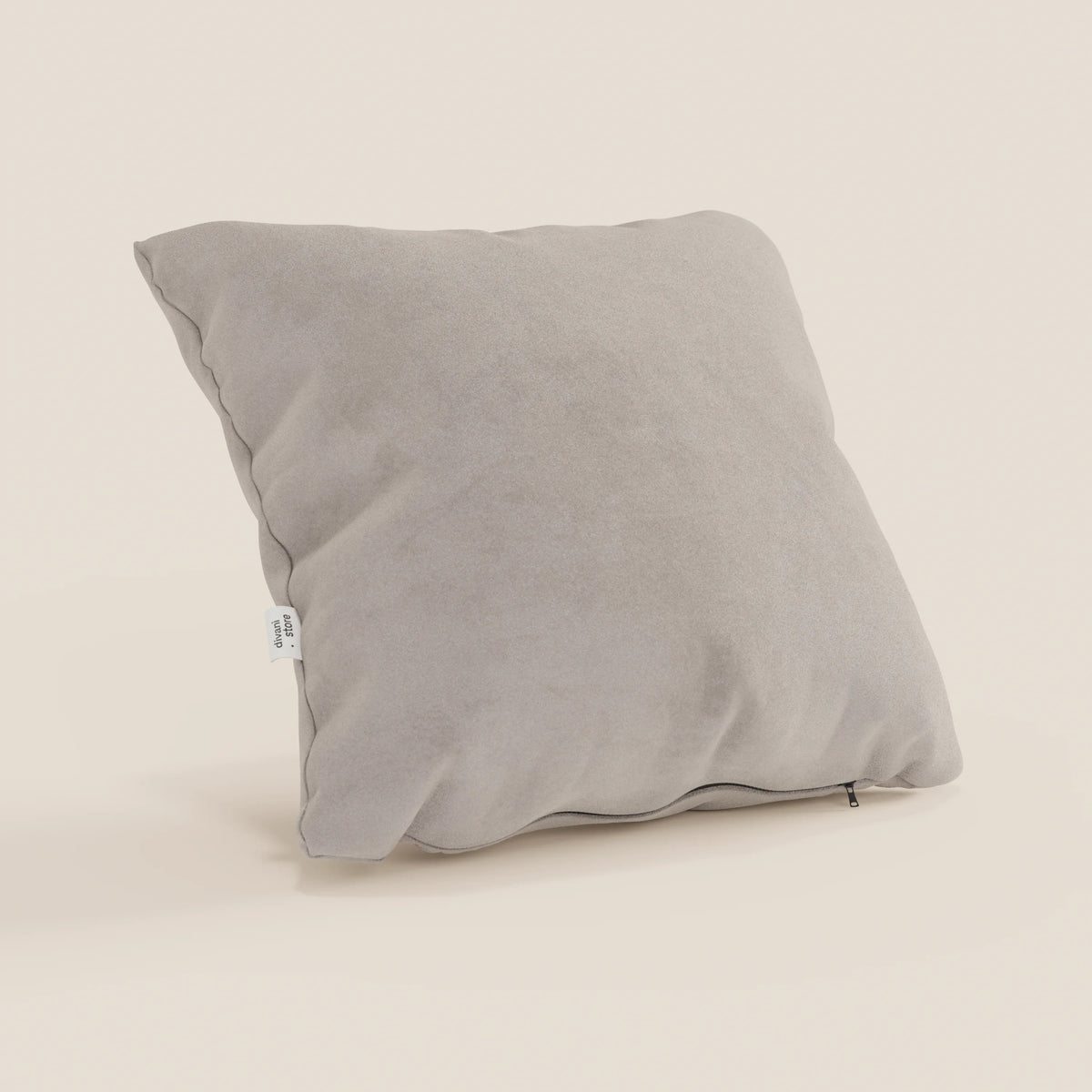 Il cuscino Jazz di divitt.sbs, 45x45 in microfibra antimacchia T11 tortora, è presentato con un morbido rivestimento effetto alcantara, angoli rientranti, targhetta in tessuto bianco e cerniera inferiore a vista su sfondo beige.