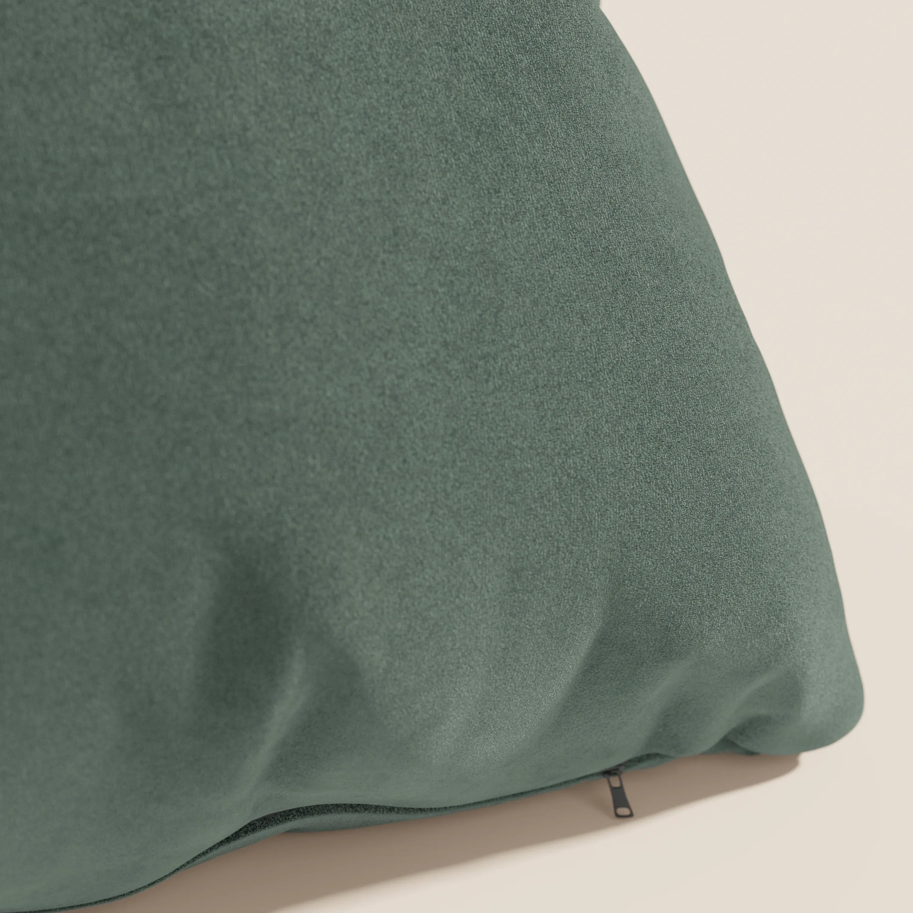 Primo piano del cuscino Jazz 45x45 di divitt.sbs in T11 verde, realizzato in microfibra tecnica antimacchia. Il cuscino verde scuro è morbido al tatto, con pieghe sottili e una cerniera nera sul bordo inferiore su uno sfondo beige chiaro.
