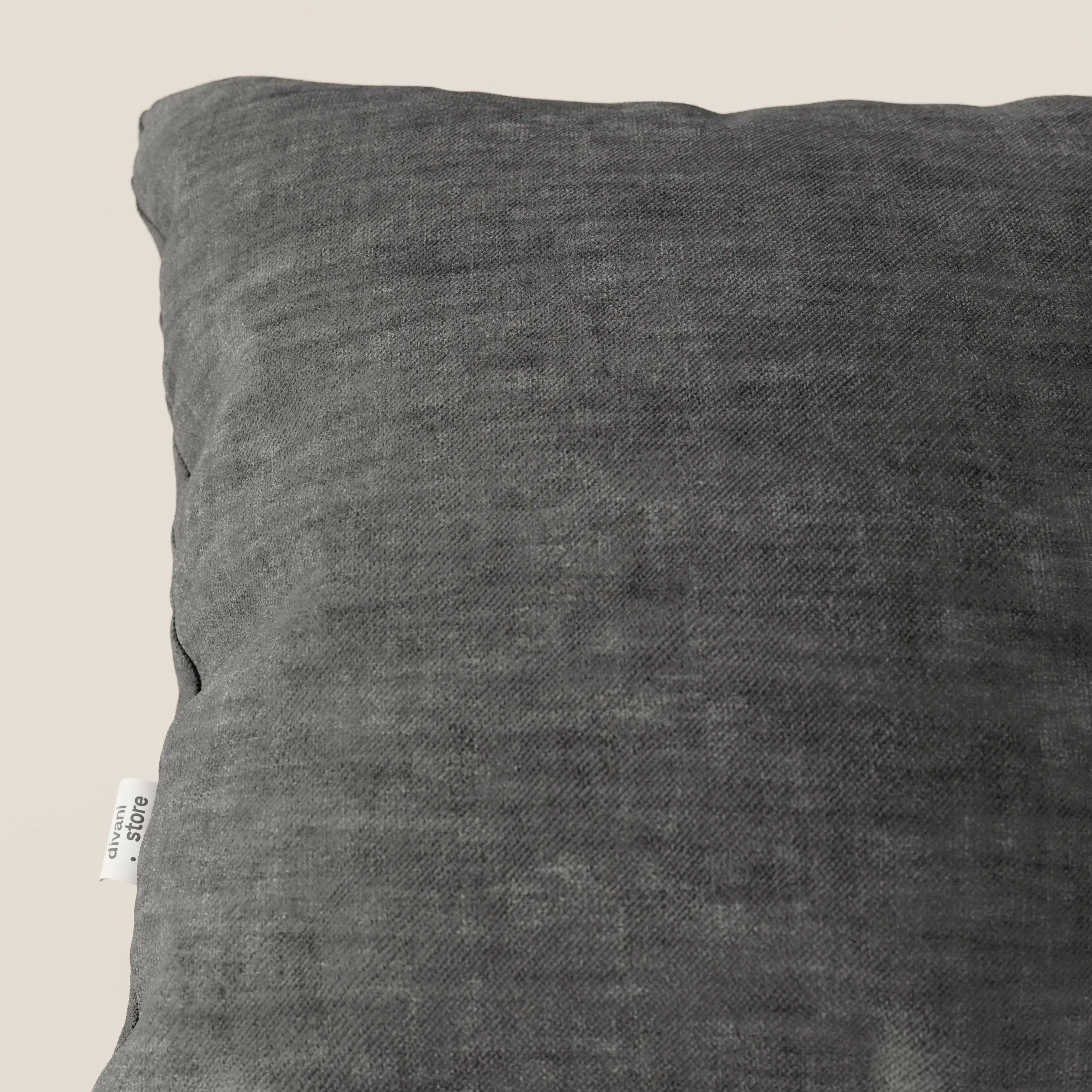Primo piano del cuscino Sofia di divitt.sbs in grigio scuro, realizzato in morbido velluto Easy Clean T35, antimacchia e impermeabile, con una piccola etichetta bianca sul lato. La texture felpata gli conferisce un aspetto accogliente sullo sfondo chiaro.