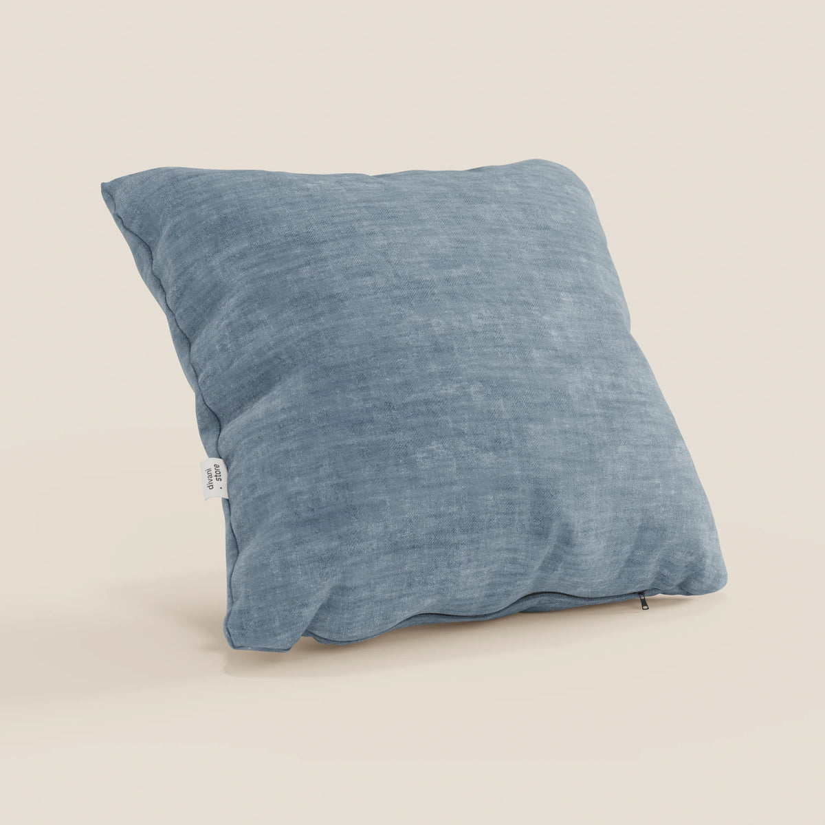 Il cuscino Sofia di divitt.sbs, in velluto nuvolato smacchiabile e impermeabile Easy Clean T35, è proposto in vari colori. Qui è raffigurato nella versione azzurra con zip sul bordo inferiore e piccolo tag laterale su sfondo beige.