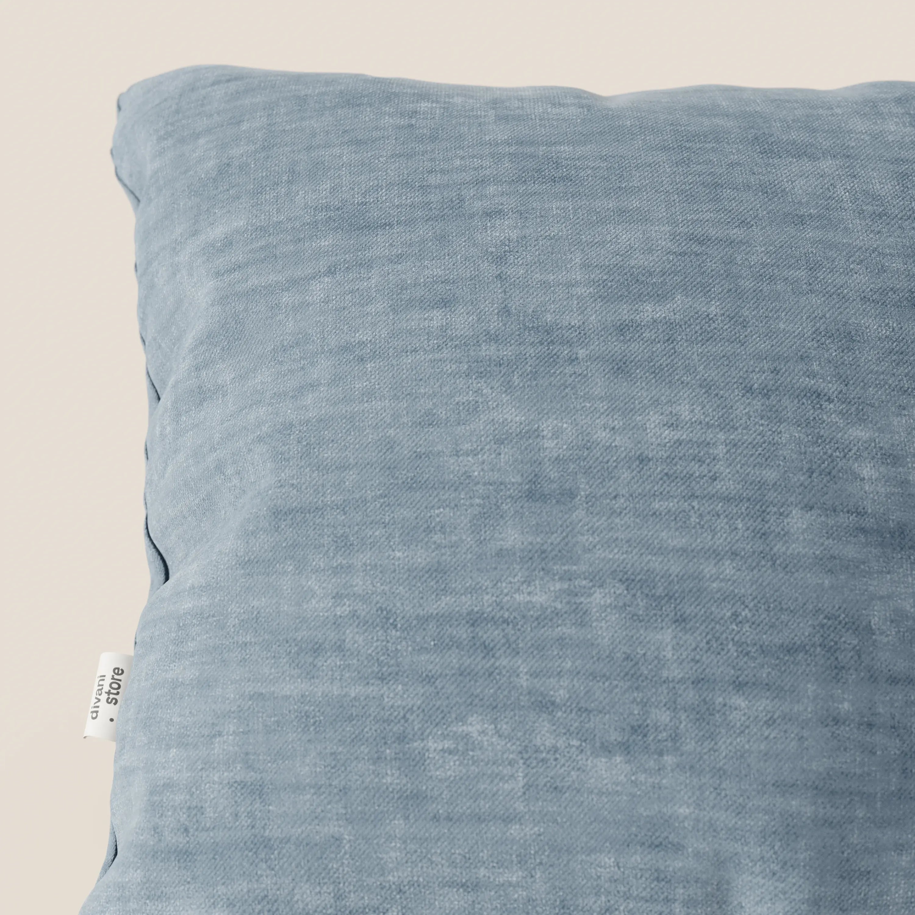 Primo piano del cuscino Sofia di divitt.sbs, in velluto nuvolato azzurro. Il tessuto Easy Clean T35, morbido, antimacchia e impermeabile, presenta un'etichetta laterale con il marchio. Lo sfondo è semplice e neutro.