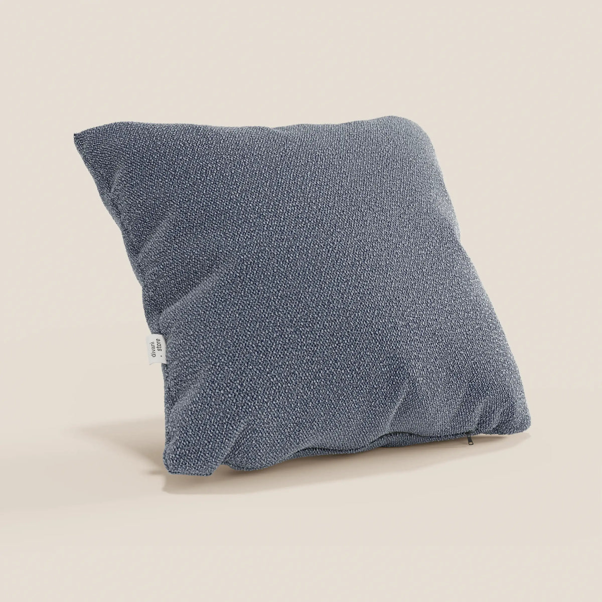 Il cuscino Lambada di divitt.sbs, qui presentato nel colore grigio-blu, è caratterizzato da un tessuto T33 antimacchia e impermeabile in simil-cotone, con una texture sottile, una forma morbida e squadrata e una piccola etichetta bianca sulla cucitura sinistra.