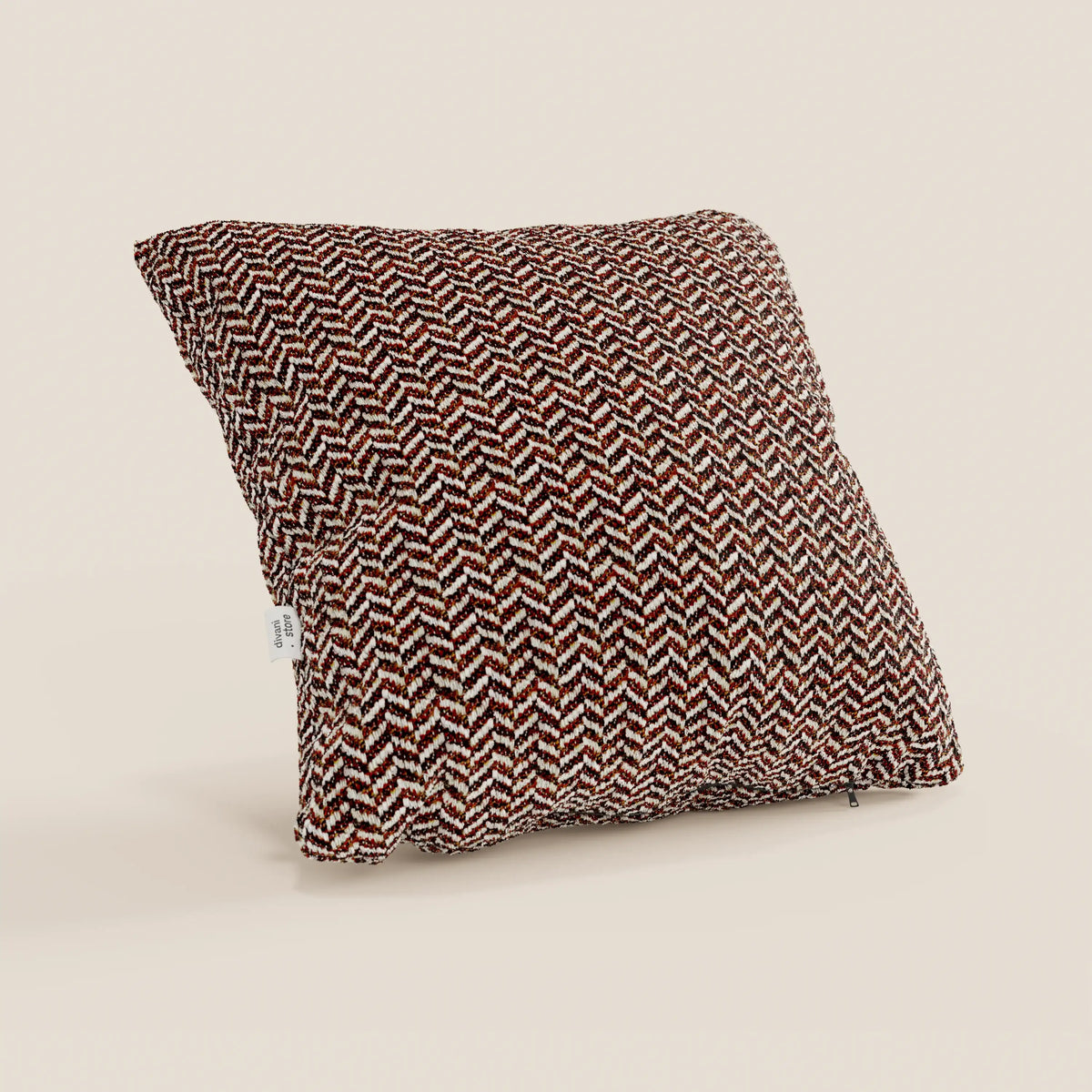 Il cuscino Sorrento 45x45 in lino di divitt.sbs è un cuscino quadrato con un motivo a spina di pesce nei colori marrone, rosso e bianco, realizzato in morbido tessuto testurizzato con una piccola etichetta bianca sul lato, raffigurato in posizione verticale su uno sfondo neutro.