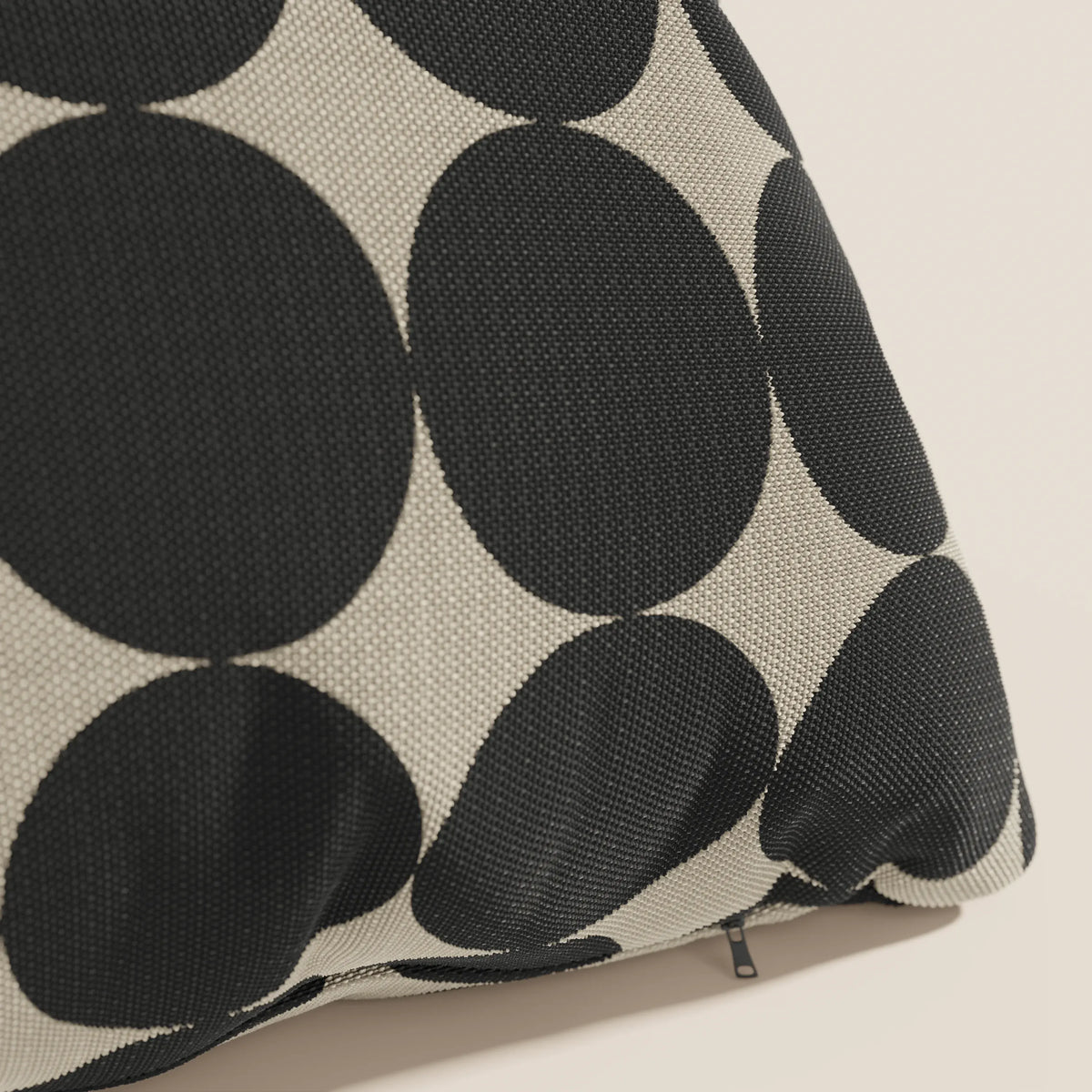 Primo piano dei cuscini geometrici Dot di divitt.sbs in tessuto tortora idrorepellente, caratterizzati da un'audace fantasia a cerchi geometrici neri e beige e da una piccola cerniera nera vicino al bordo.