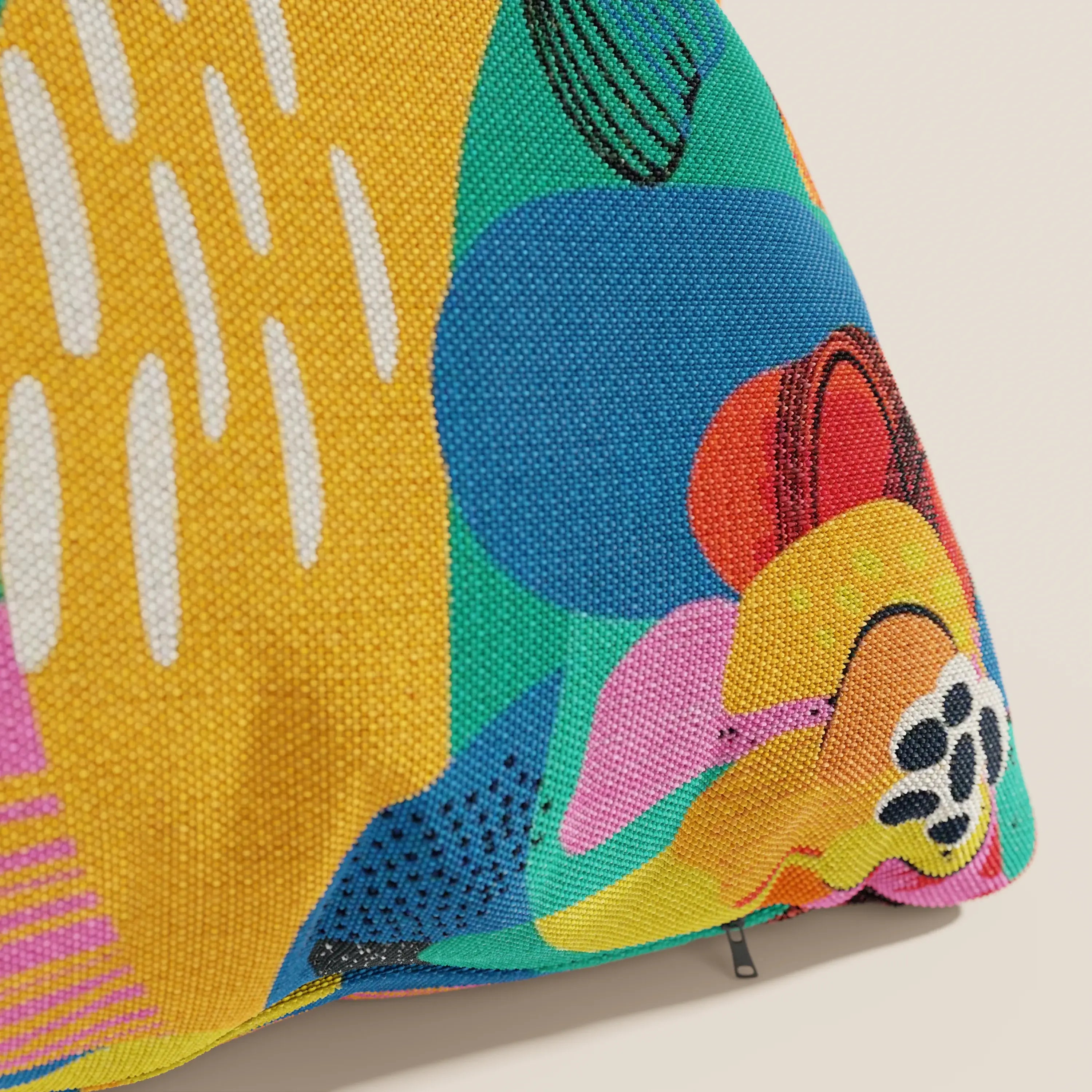 Primo piano della collezione Joy cuscini di divitt.sbs, caratterizzata da vivaci forme astratte in giallo, verde, blu, rosa, arancione e nero su un fresco tessuto di cotone impermeabile giallo con punti e linee.