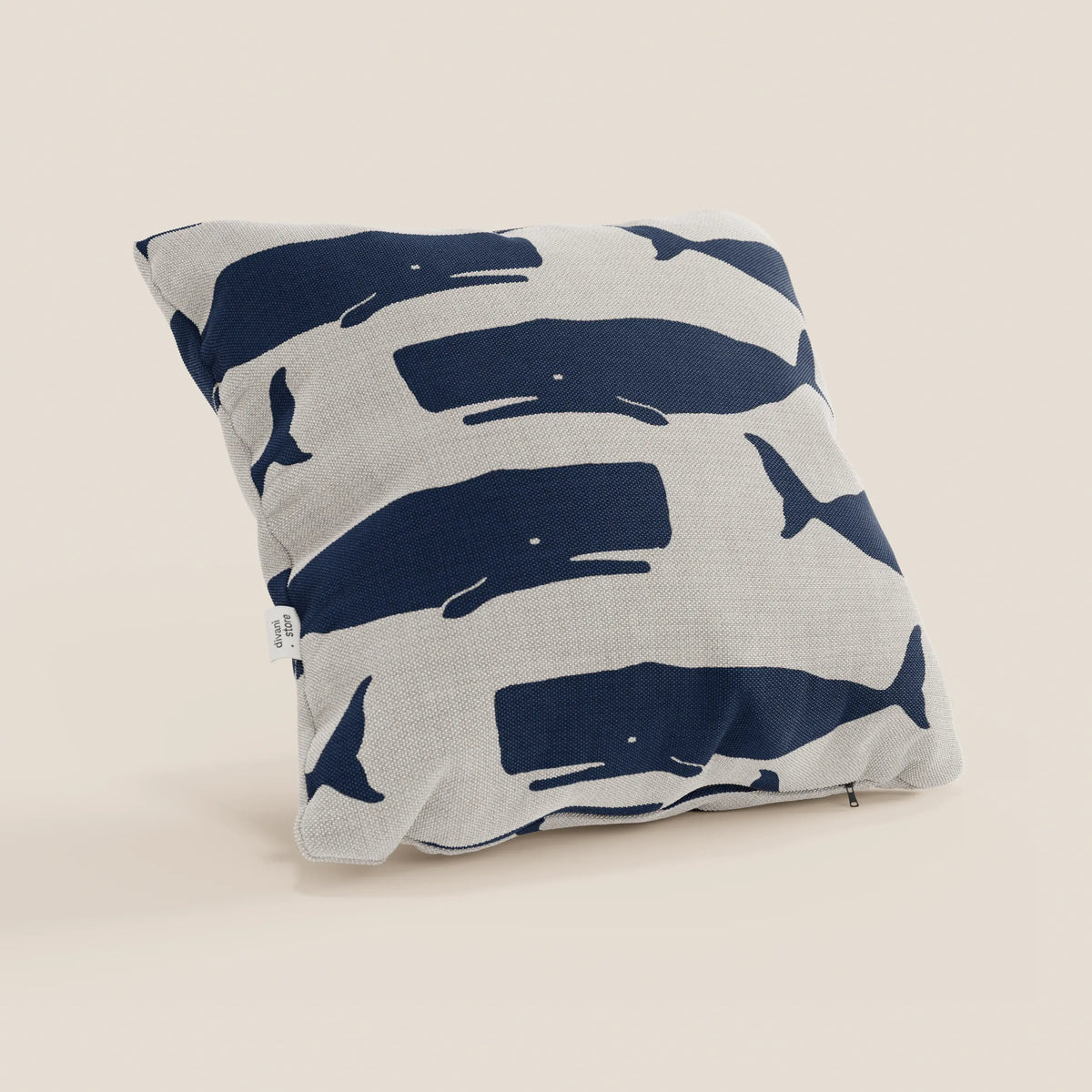 Il cuscino quadrato Nautilus di divitt.sbs, in tessuto impermeabile, presenta balene blu su sfondo beige e un'etichetta bianca; perfetto per aggiungere stile marino alla tua casa.