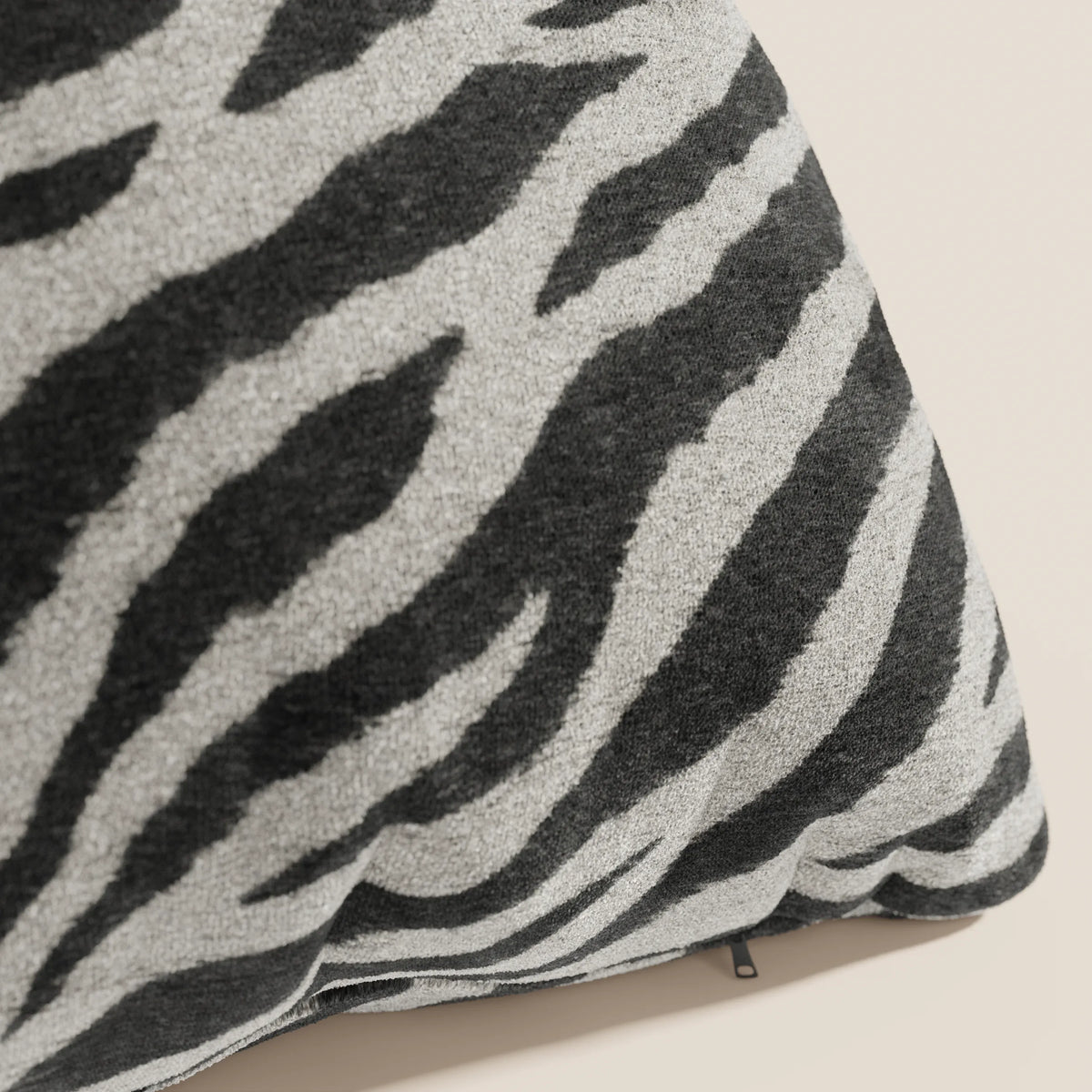 Primo piano del cuscino Wild 45x45 della collezione Wild di divitt.sbs, caratterizzato da un motivo zebrato nero e grigio chiaro su microfibra impermeabile beige, con texture morbida, cuciture a vista e una cerniera lungo il bordo inferiore.