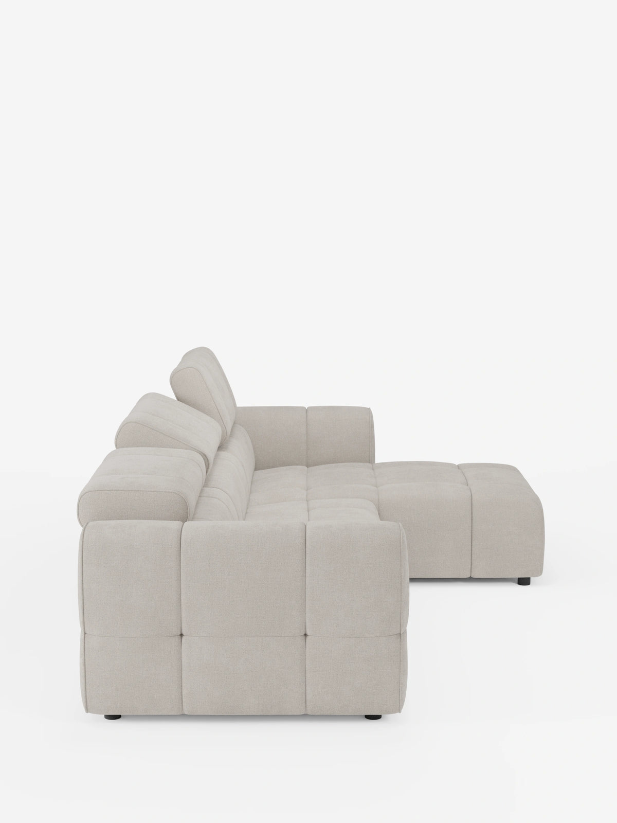 Una vista laterale del divano angolare modulare Giotto a 5 posti da 296 cm con penisola e funzione relax elettrica opzionale, rivestito in tessuto smacchiabile T23: un divano modulare color beige chiaro con braccioli bassi e squadrati, seduta trapuntata, poggiatesta regolabili e piedini scuri.