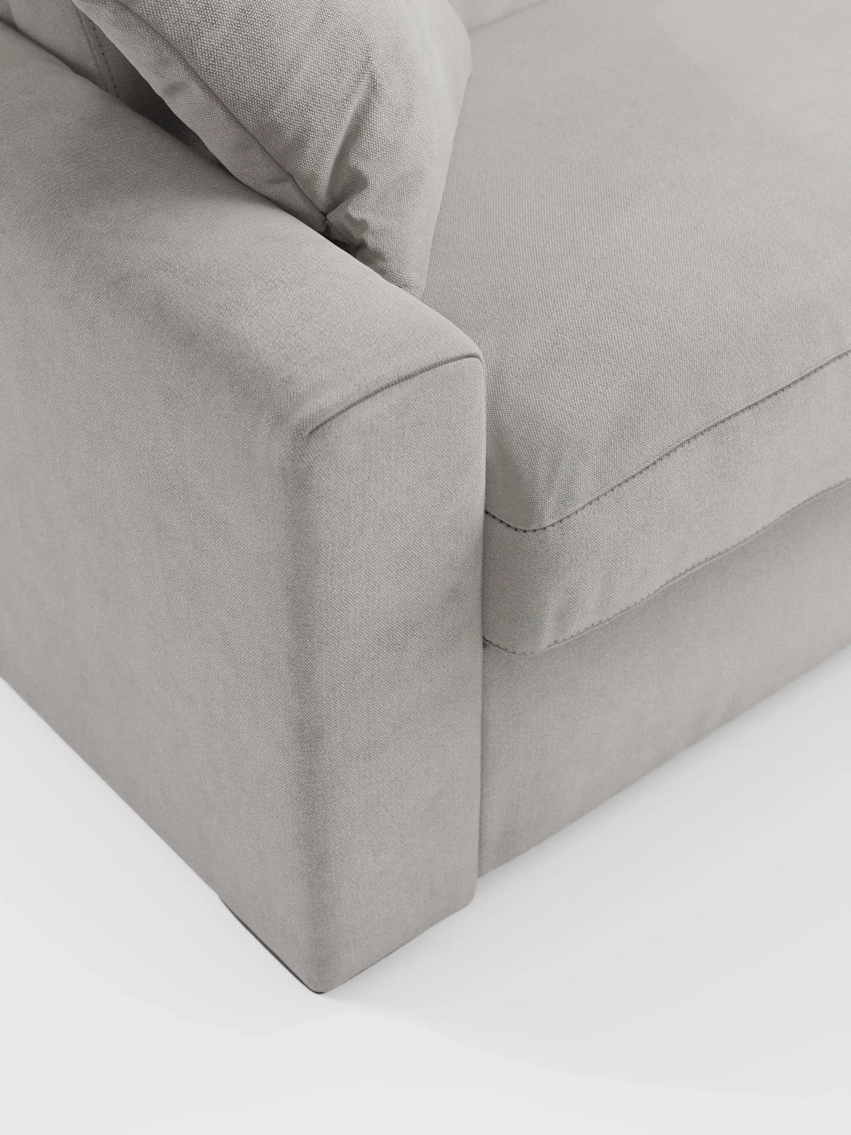 Primo piano del divano letto Maximus a 3 posti con materasso ALTO da 20 cm di divitt.sbs, caratterizzato da braccioli spessi, un morbido cuscino di seduta e un cuscino dello schienale abbinato in tessuto grigio chiaro Oeko-Tex resistente alle macchie. Su uno sfondo bianco, le sue linee pulite e la possibilità di scegliere poggiatesta reclinabili mettono in risalto il design minimalista e contemporaneo del divano.