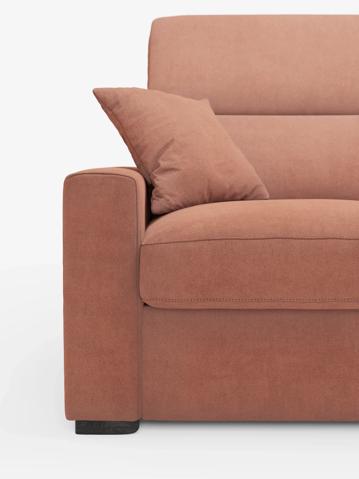 Primo piano del divano letto a 3 posti Maximus di divitt.sbs con materasso ALTO da 20 cm, rivestito in tessuto Oeko-Tex color terracotta tenue e resistente alle macchie. L'immagine mette in risalto il bracciolo sinistro, il cuscino della seduta e un cuscino decorativo abbinato. Il divano presenta linee pulite, cuciture a vista, poggiatesta reclinabili regolabili per un maggiore comfort e poggia su gambe corte in legno scuro su uno sfondo bianco.