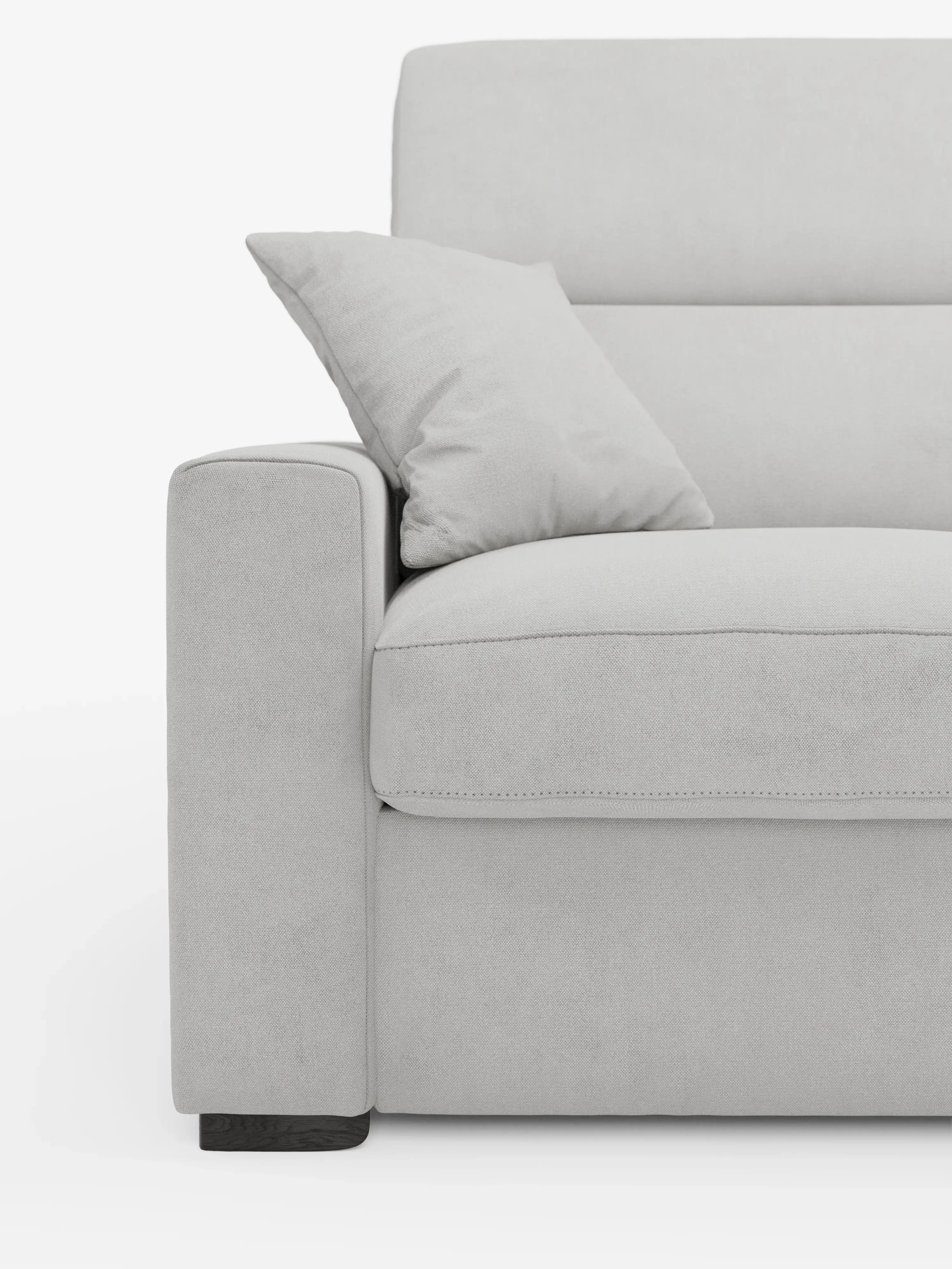 Primo piano del divano letto Maximus a 3 posti con materasso ALTO 20 cm di divitt.sbs, in una moderna finitura grigio chiaro. L'immagine mette in risalto il bracciolo sinistro, parte della seduta imbottita e un cuscino coordinato. Caratterizzato da linee pulite e da un design minimalista, questo divano presenta cuciture a vista sui bordi e poggiatesta reclinabili. Rivestito in tessuto smacchiabile Oeko-Tex. Lo sfondo è bianco a tinta unita.