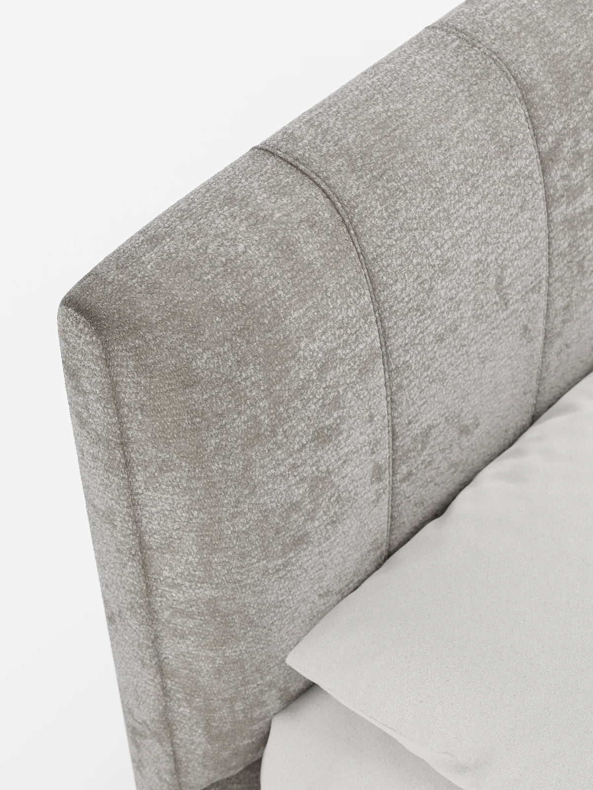 Primo piano del letto imbottito ONYX con contenitore e testiera verticale in tessuto certificato Oeko-Tex®, caratterizzato da una testiera moderna con trapuntatura a canali verticali in tessuto color taupe chiaro, accanto a un cuscino bianco.