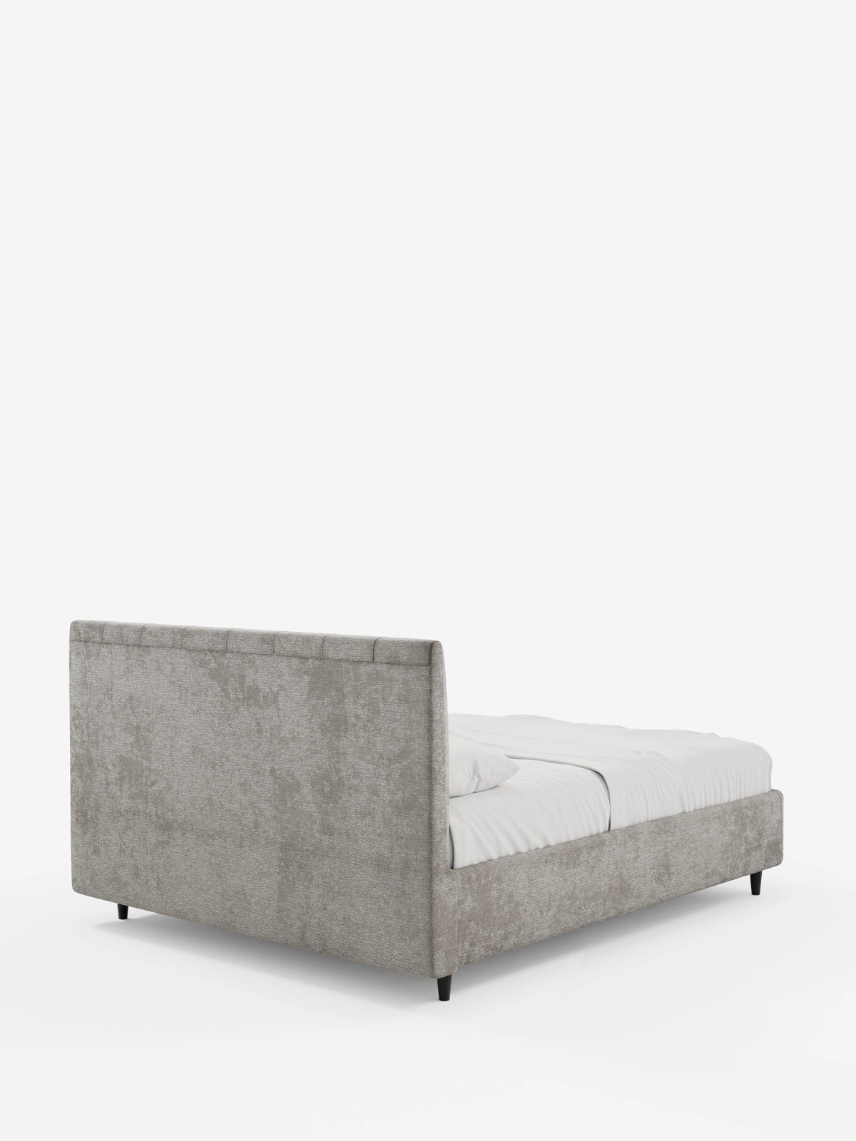 Un letto imbottito ONYX dai toni neutri, con contenitore e testiera verticale in tessuto certificato Oeko-Tex®, con una testiera alta e cucita verticalmente, visto dall’angolo posteriore su gambe scure con semplice biancheria da letto bianca.