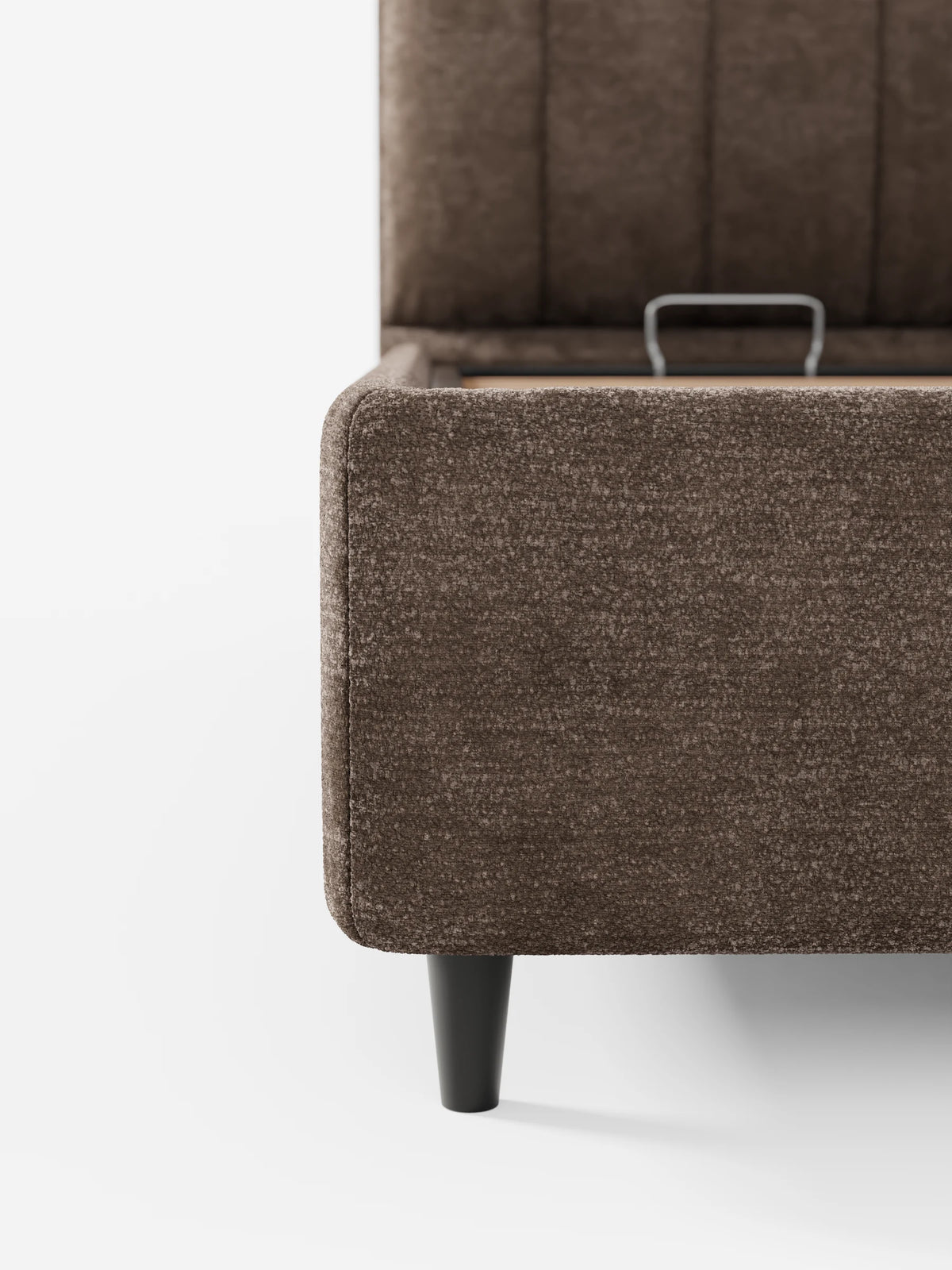Un primo piano del letto imbottito ONYX con contenitore e testiera verticale in tessuto certificato Oeko-Tex® color marrone, caratterizzato da una testiera alta a pannelli, una maniglia in metallo sul telaio interno e una gamba scura affusolata.