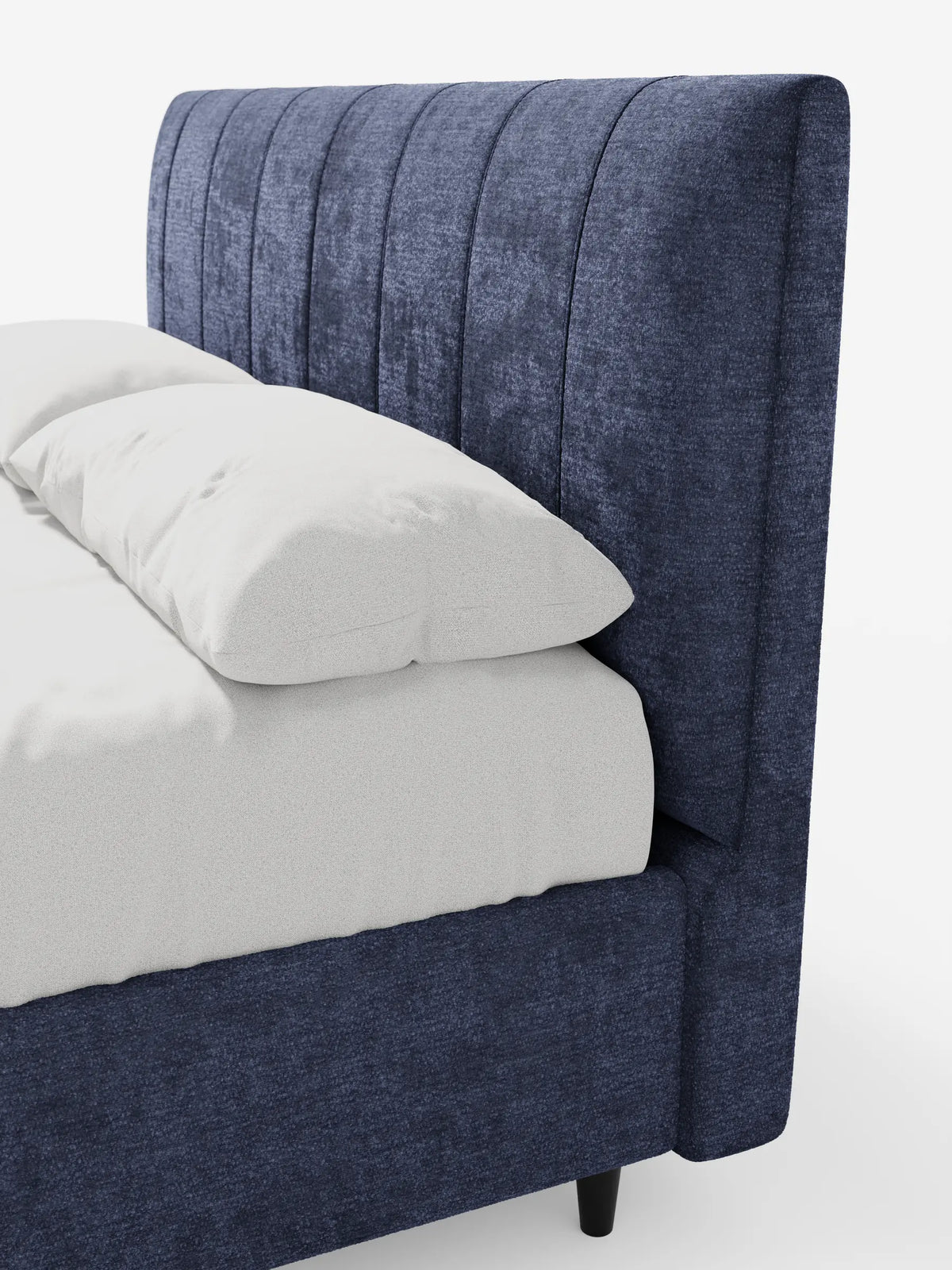 Il letto imbottito ONYX con contenitore e testiera verticale in tessuto certificato Oeko-Tex® è un letto moderno di colore blu intenso, caratterizzato da una testiera alta con scanalature verticali e due cuscini bianchi, che risaltano su uno sfondo bianco a tinta unita.