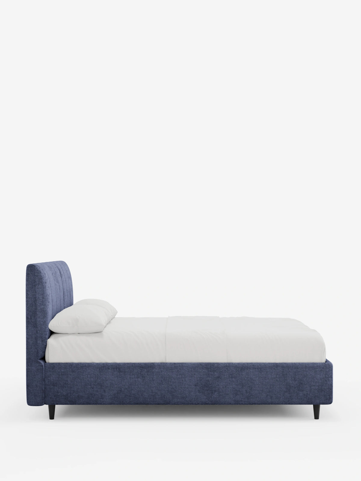 Una vista laterale del letto imbottito ONYX con contenitore e testiera verticale in tessuto certificato Oeko-Tex®, caratterizzato da un'alta testiera a pannelli verticali in tessuto blu scuro, biancheria da letto bianca e sottili gambe nere su uno sfondo bianco a tinta unita.