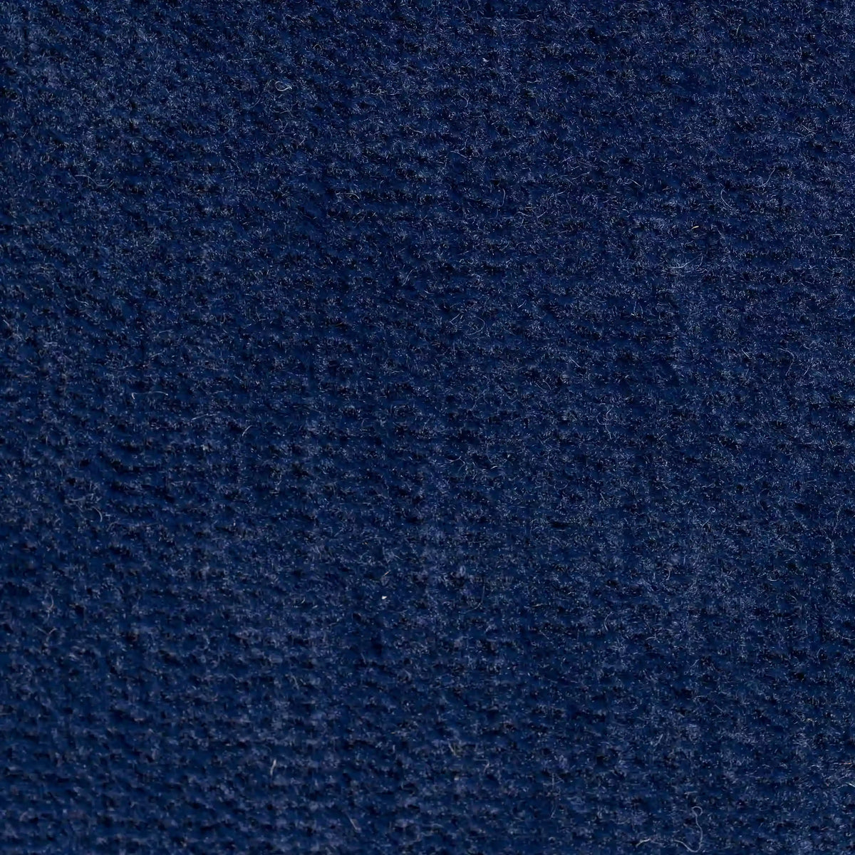 Primo piano del cuscino Bolero di divitt.sbs in tessuto T31 blu scuro, caratterizzato da una superficie morbida e strutturata con sottili creste. Il materiale smacchiabile, impermeabile e irrestringibile offre colori ricchi e sottili variazioni di sfumature.