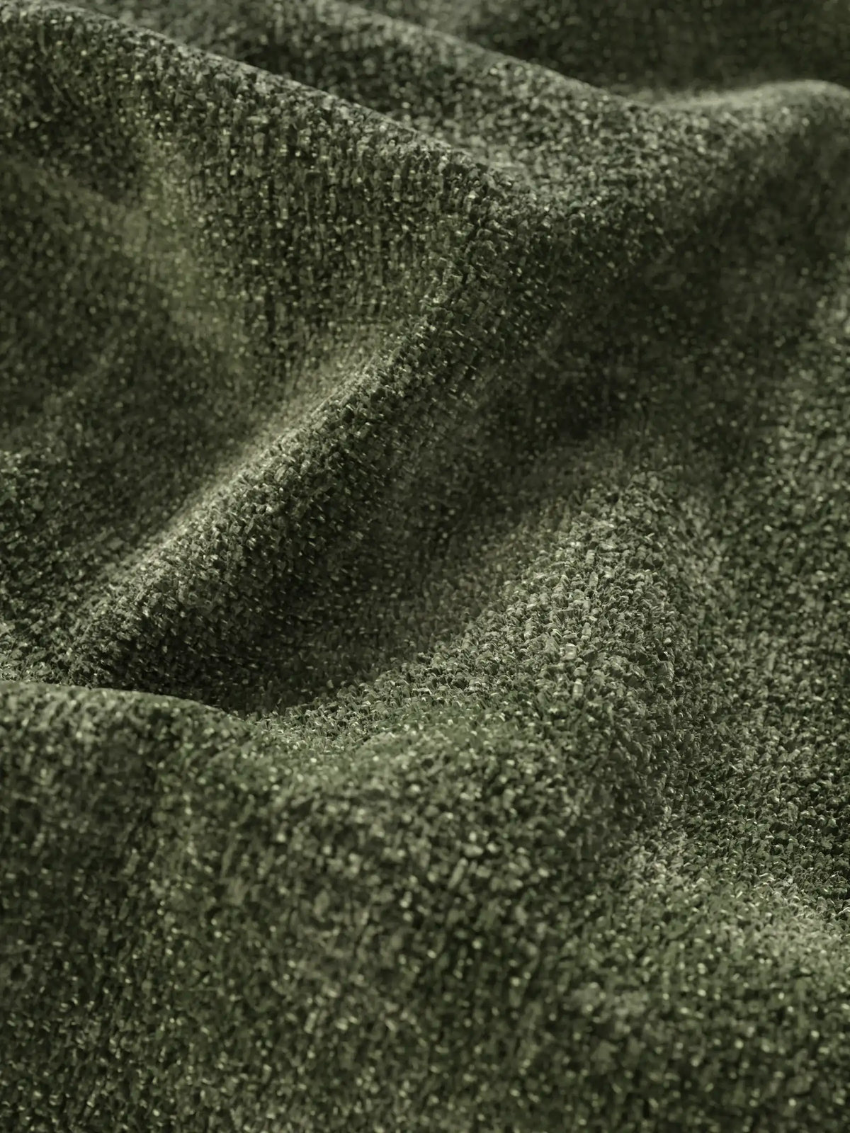Primo piano del tessuto verde oliva dalla trama rigata su un divano letto Ottaviano con letto estraibile – penisola reversibile e contenitore in tessuto materico lavabile, che mostra un motivo fitto e intrecciato con morbide pieghe e giochi di ombra.