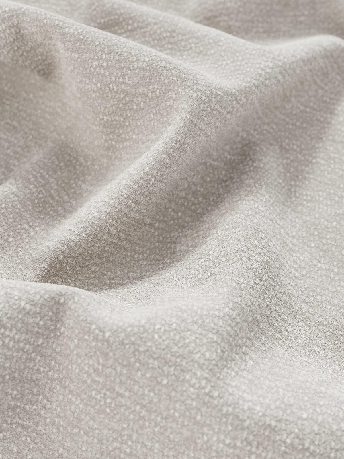 Primo piano del letto imbottito ONYX con contenitore e testiera verticale in tessuto certificato Oeko-Tex®, che mostra un tessuto beige chiaro, dalla trama ruvida, arricciato in morbide pieghe con un intreccio screziato e una finitura opaca.