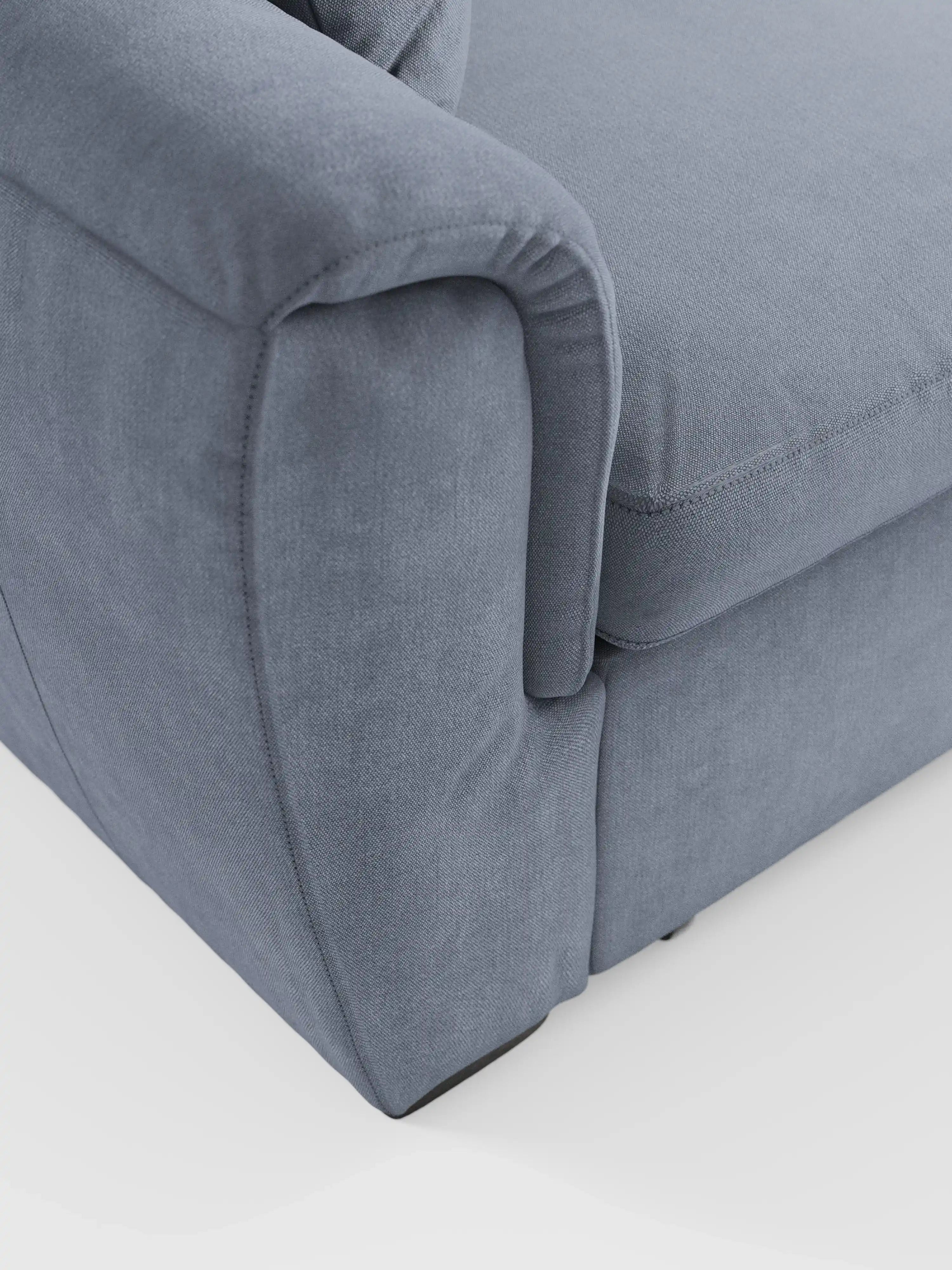 Primo piano del bracciolo e della seduta del divano Titano a 2 posti estraibile con poggiatesta reclinabili in tessuto smacchiabile Oeko-Tex® di divitt.sbs, raffigurato in un moderno tessuto grigio chiaro su sfondo bianco. Il rivestimento morbido e facile da pulire presenta cuciture a vista e un'imbottitura soffice che garantisce comfort e un look contemporaneo. La silhouette versatile di questo divano compatto coniuga perfettamente stile e funzionalità, rendendolo la scelta ideale per gli spazi moderni.