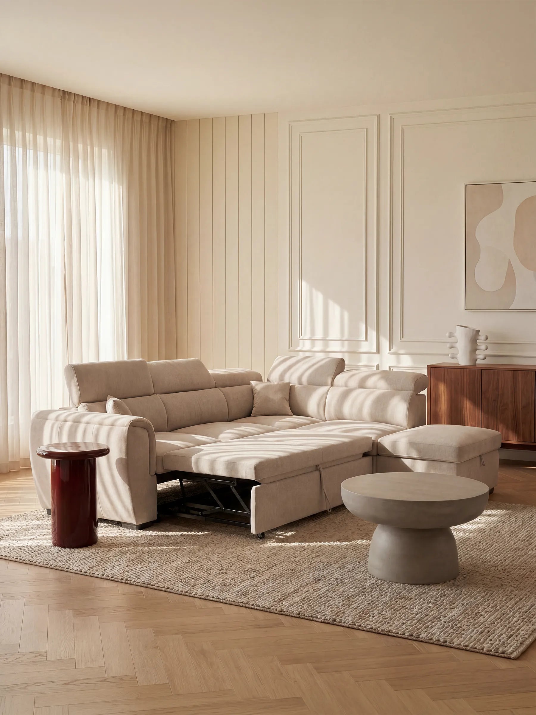 Il divano angolare reversibile Titano con letto estraibile e pouf contenitore di Divani.Il divano, caratterizzato da poggiatesta reclinabili e rivestimento in tessuto smacchiabile Oeko-Tex®, è posizionato su un tappeto testurizzato in un luminoso soggiorno moderno con pavimenti in legno, tende leggere, opere d’arte astratta alle pareti e tavolini minimalisti. La luce naturale avvolge l’ambiente, creando un’atmosfera accogliente e invitante.