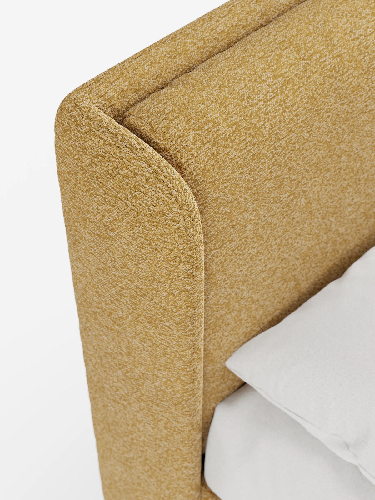 Primo piano di un letto di design VALKIRIA color giallo senape con vano contenitore e testiera avvolgente, caratterizzato da una struttura imbottita con bordi curvi e avvolgenti su sfondo bianco, accanto a un cuscino bianco.