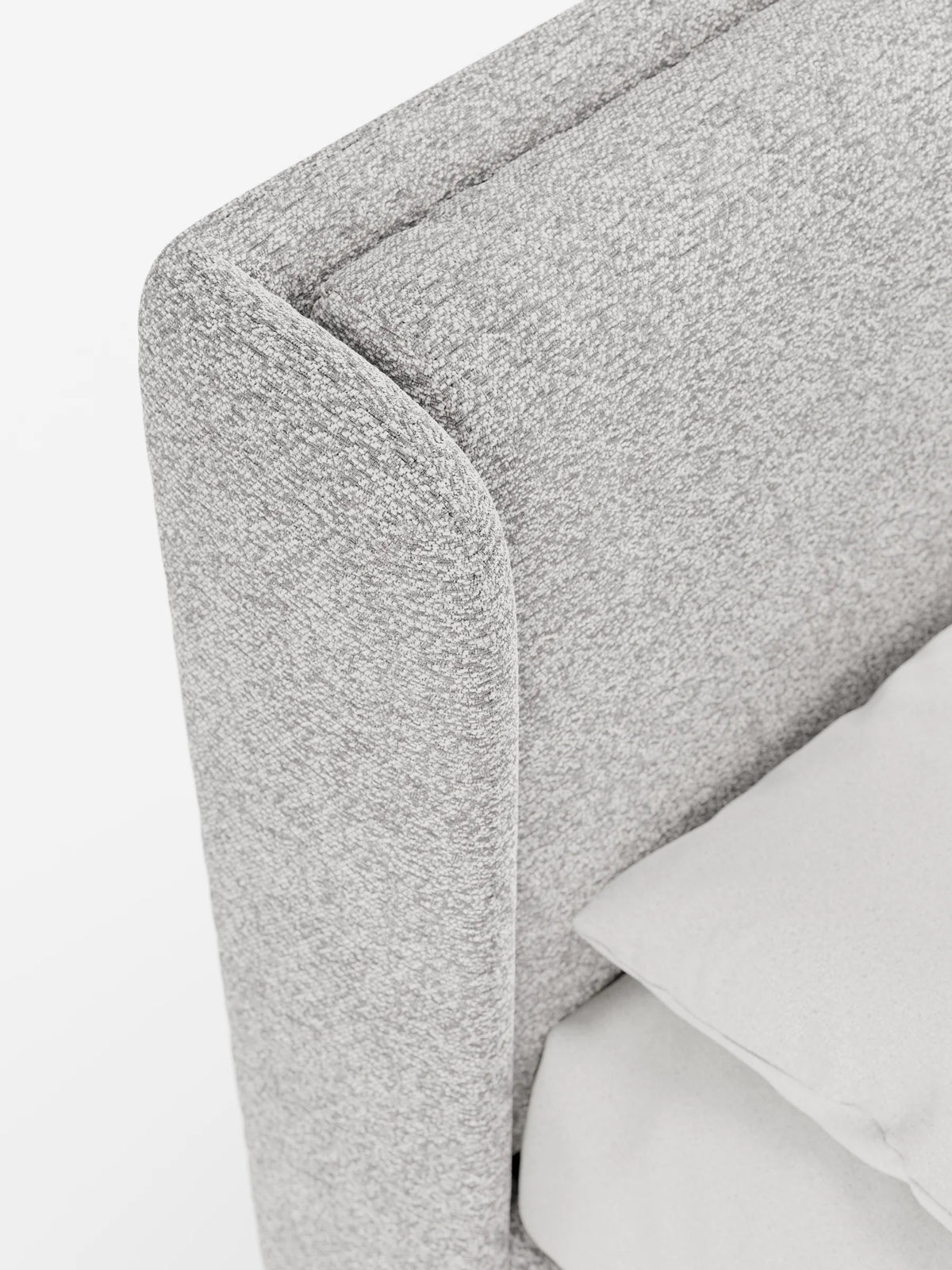 Un primo piano del letto di design VALKIRIA con contenitore e testiera avvolgente - 2 cuscini imbottiti e tessuto Oeko-Tex®: presenta una testiera avvolgente di colore grigio chiaro, dalle linee curve, rivestita in tessuto testurizzato e un cuscino liscio.