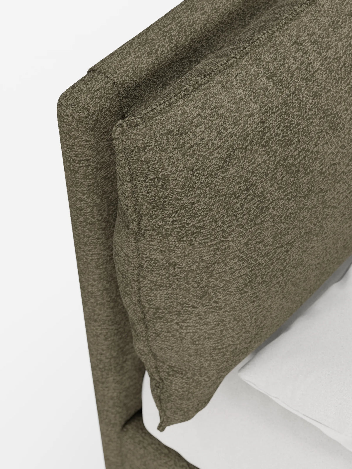 Primo piano di un letto imbottito ZAYRON con contenitore e morbidi cuscini regolabili, caratterizzato da una moderna testiera verde oliva con texture, contro la quale è appoggiato un cuscino spesso, accanto a un materasso bianco.
